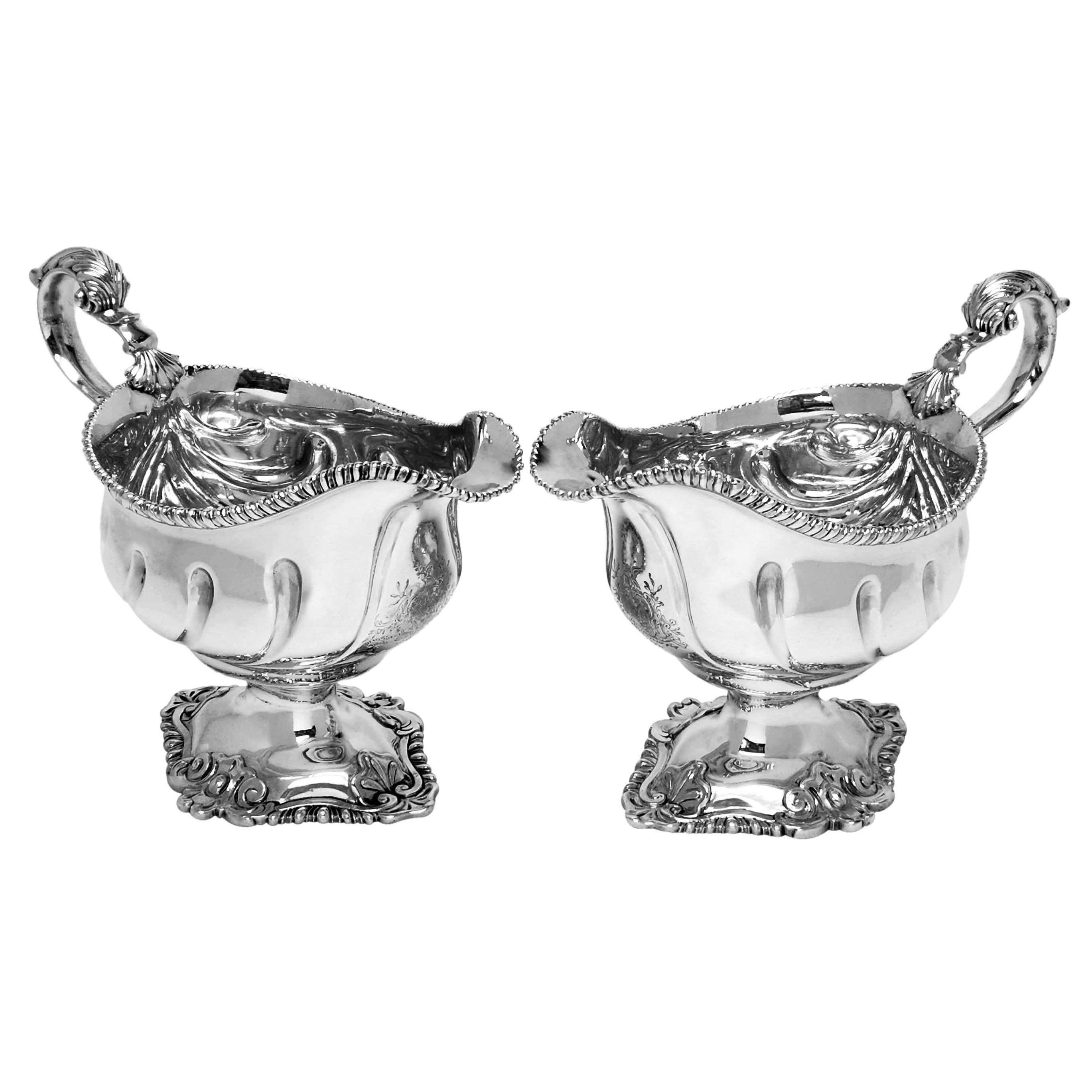 A set of 4 Antique George III sterling silver sauce boats decorated with gadroon borders on the lip and foot. The Foot is further embellished with a scroll details. Each Gravy Boat has a large armorial engraved below the spout. 
These Sauce Boats