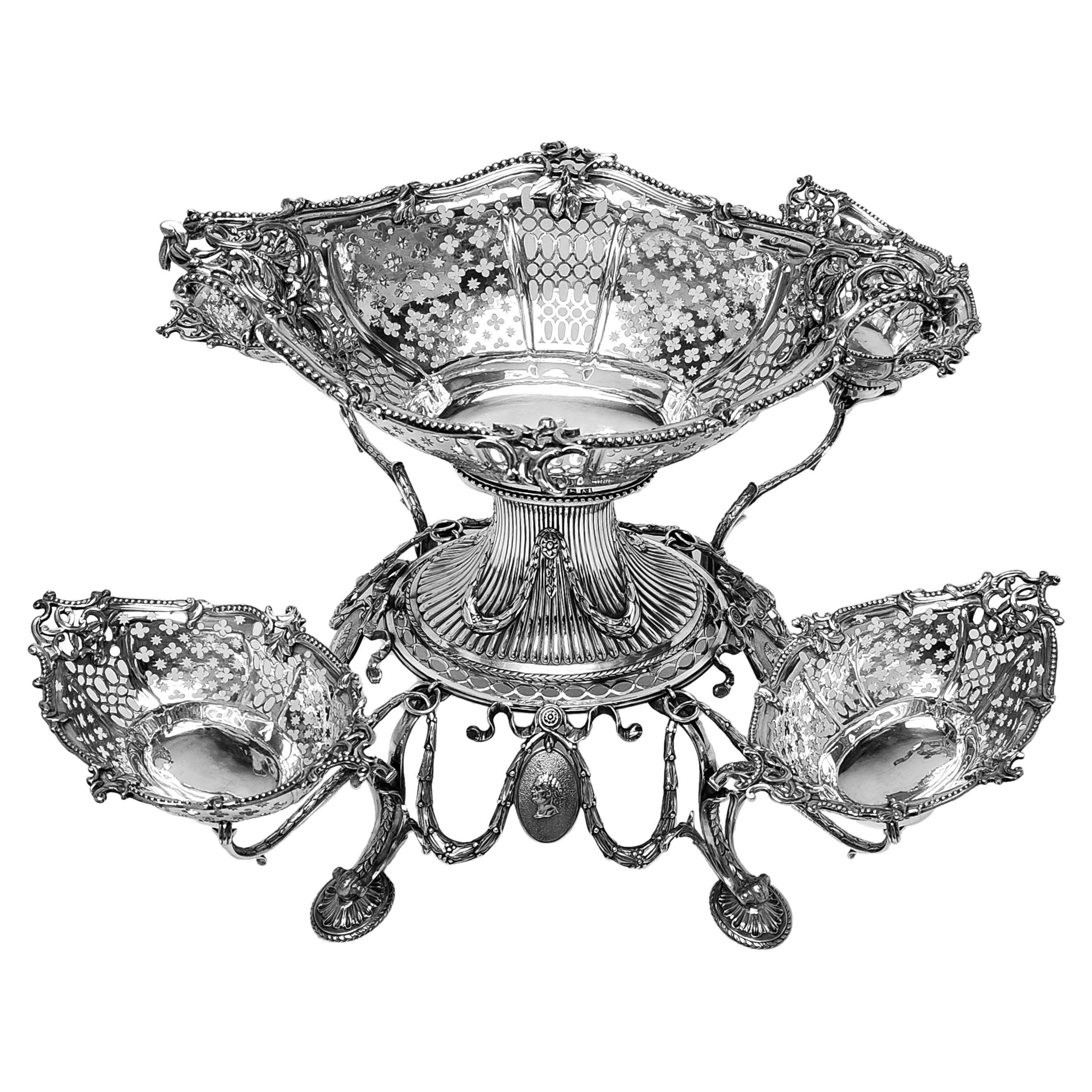 Una magnífica Epergne de Plata Georgiana Antigua de estilo clásico Adams. La Pieza Central Jorge III tiene una gran cesta central sobre un pedestal y cuatro elegantes ramas que sostienen cestas más pequeñas. Las cuatro Cestas de Plata están