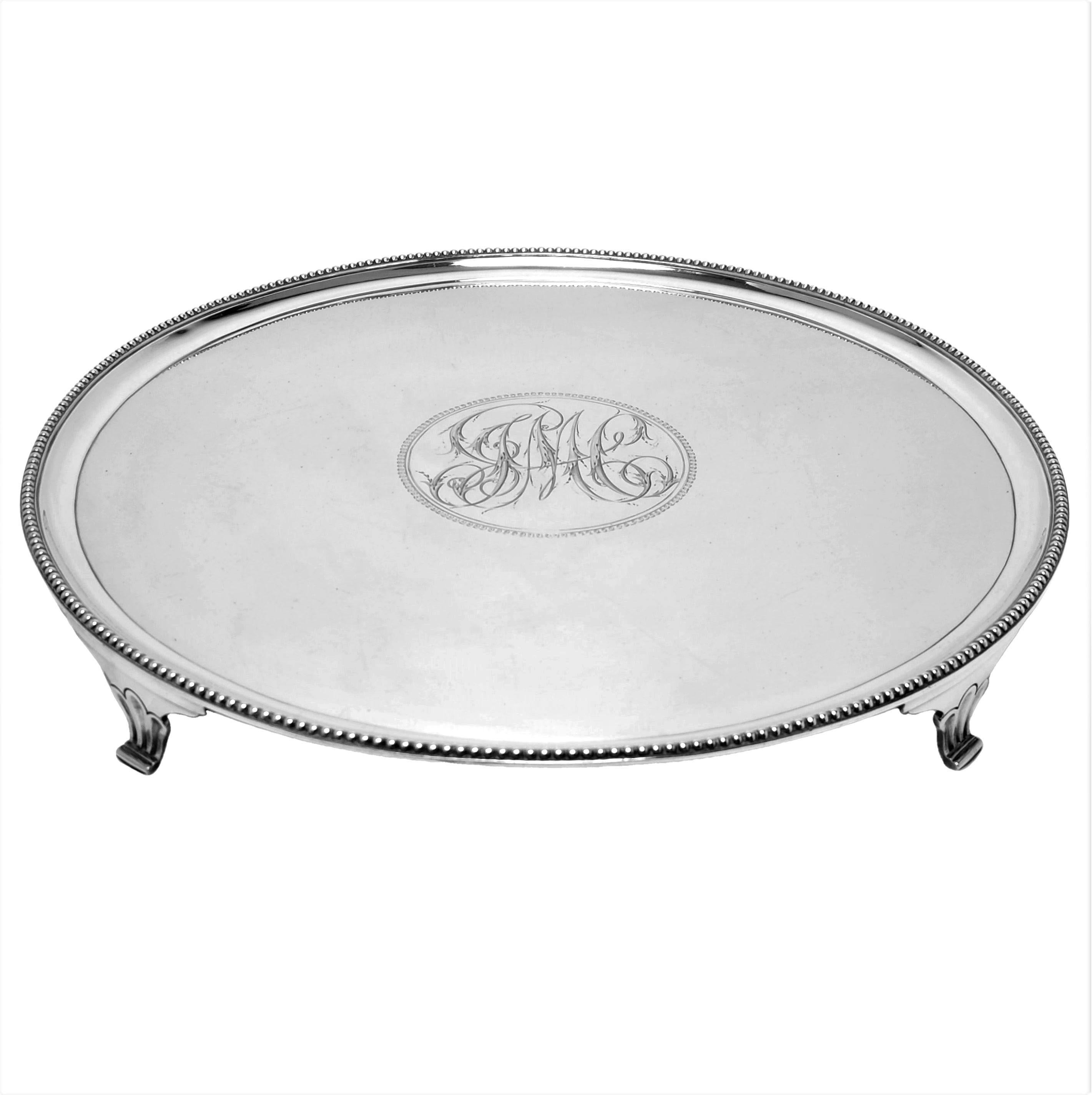 A traditional Antique George III solid silver Salver. This Salver has a round form embellished with a classic bead border and has a sizable engraved monogram in the centre. The Salver stands on four shaped feet.

Made in London, England in 1785 by