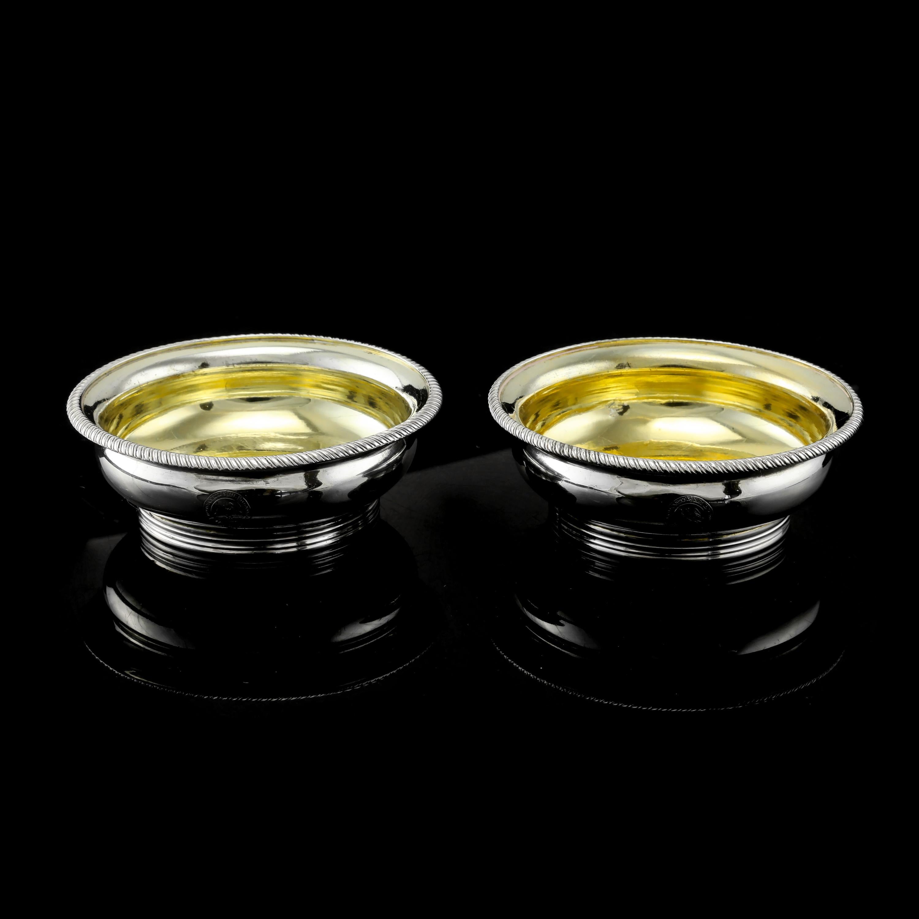 We are delighted to offer this quality pair of Georgian solid silver salt cellars made by Joseph Felix Podio in London, 1809. 
 
The pair features a plain exterior finish with a mirror-like surface, with one hand-engraved family crest and motto on