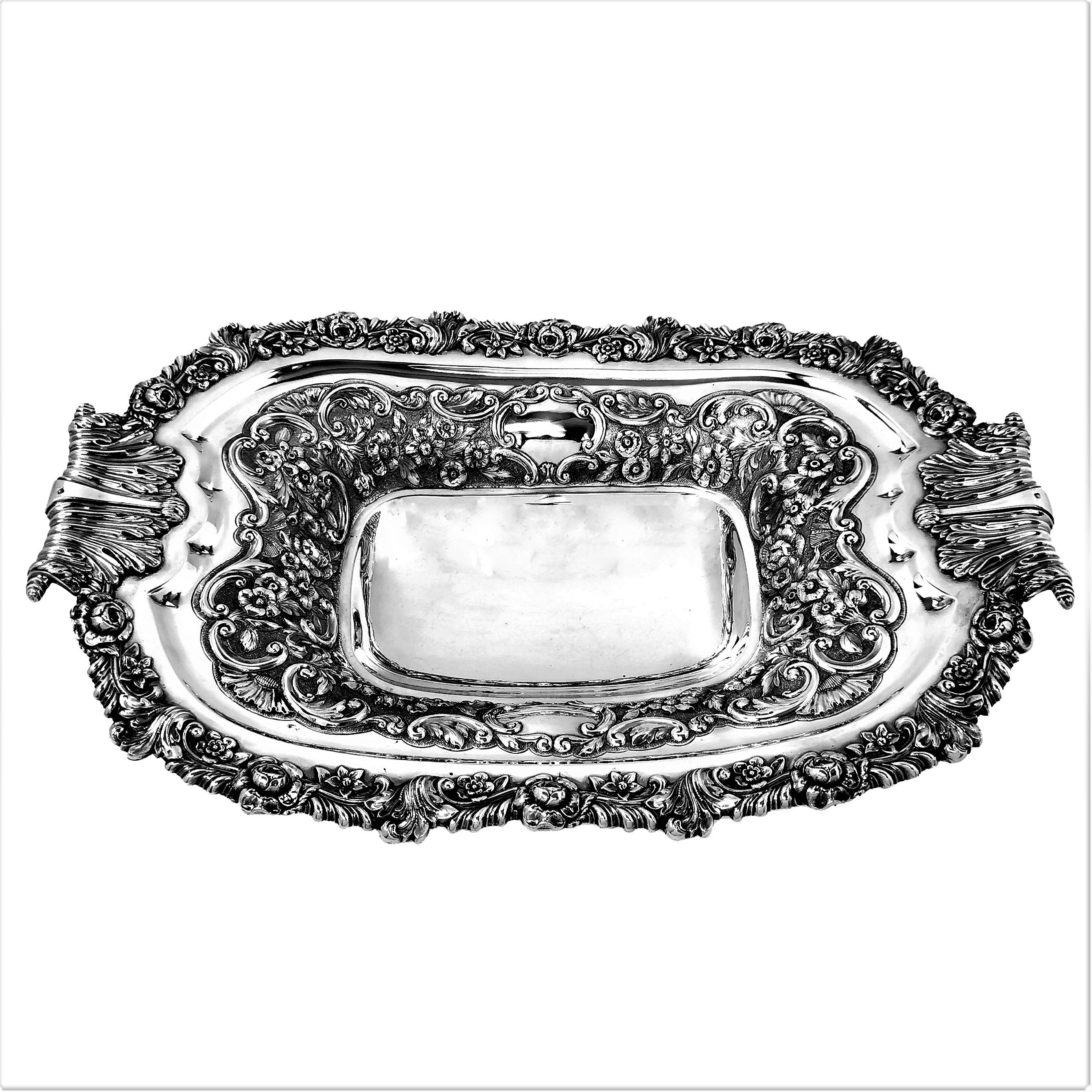 An elegant Antique George IV solid Silver Bowl or Dish with a shaped rectangular form. This Dish is decorated with a elaborate chased floral and scroll design and has complementary ornate handles integrated in this design. The Dish stands on a