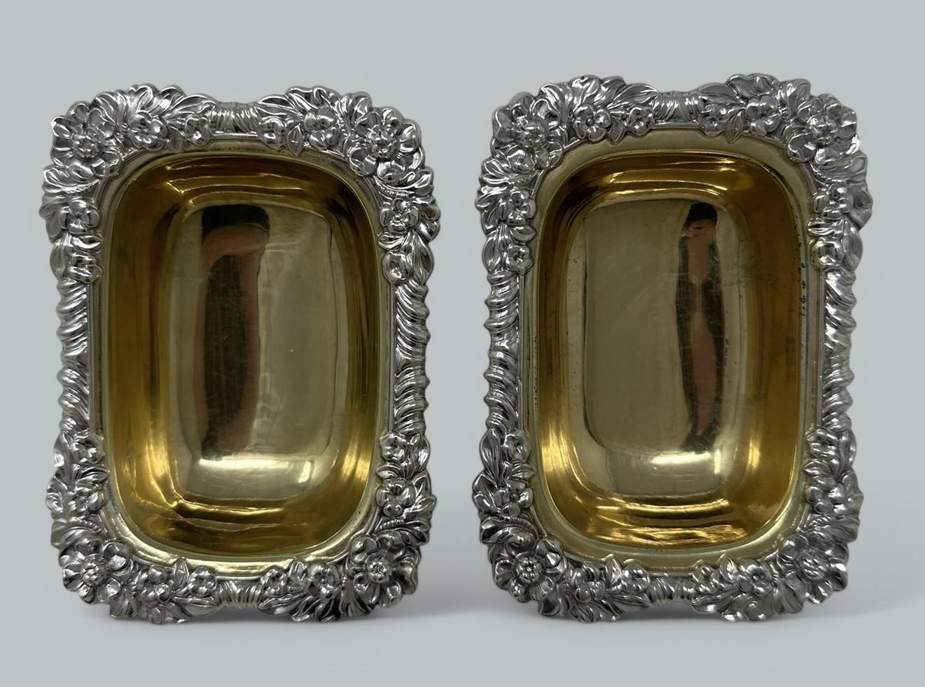 Une paire absolument stupéfiante de salières ouvertes de forme rectangulaire en argent sterling doré, de bonne qualité et de proportions généreuses.  

Chacune d'entre elles est ornée d'un élégant bord fleuri et godronné au-dessus d'un corps et
