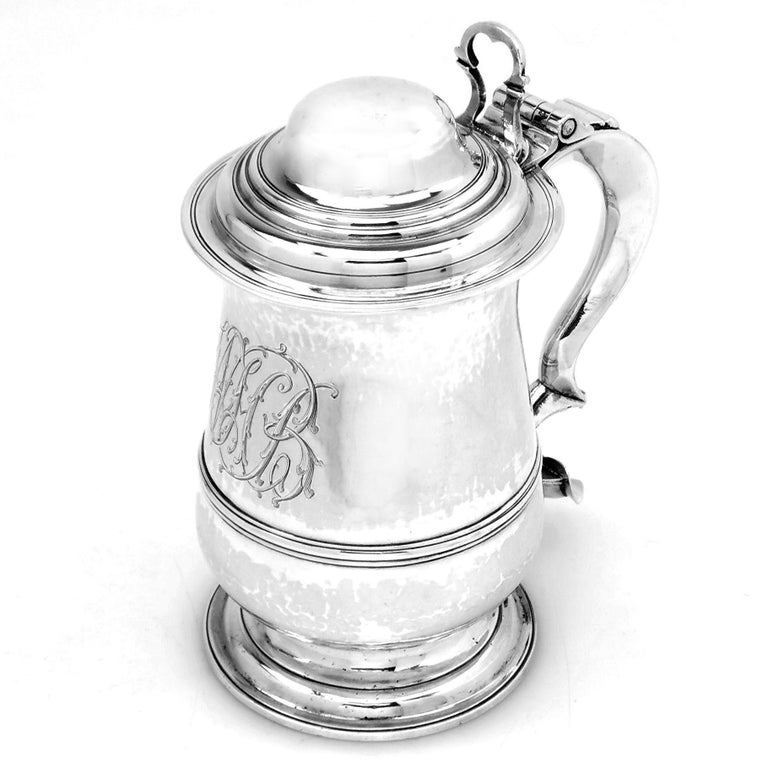 A classic Antique George III solid Silver Tankard with a traditional baluster shaped body and standing on a spread pedestal foot. The Lidded Beer Tankard has an ornate monogram engraved opposite the substantial scroll handle. 

Made in London in