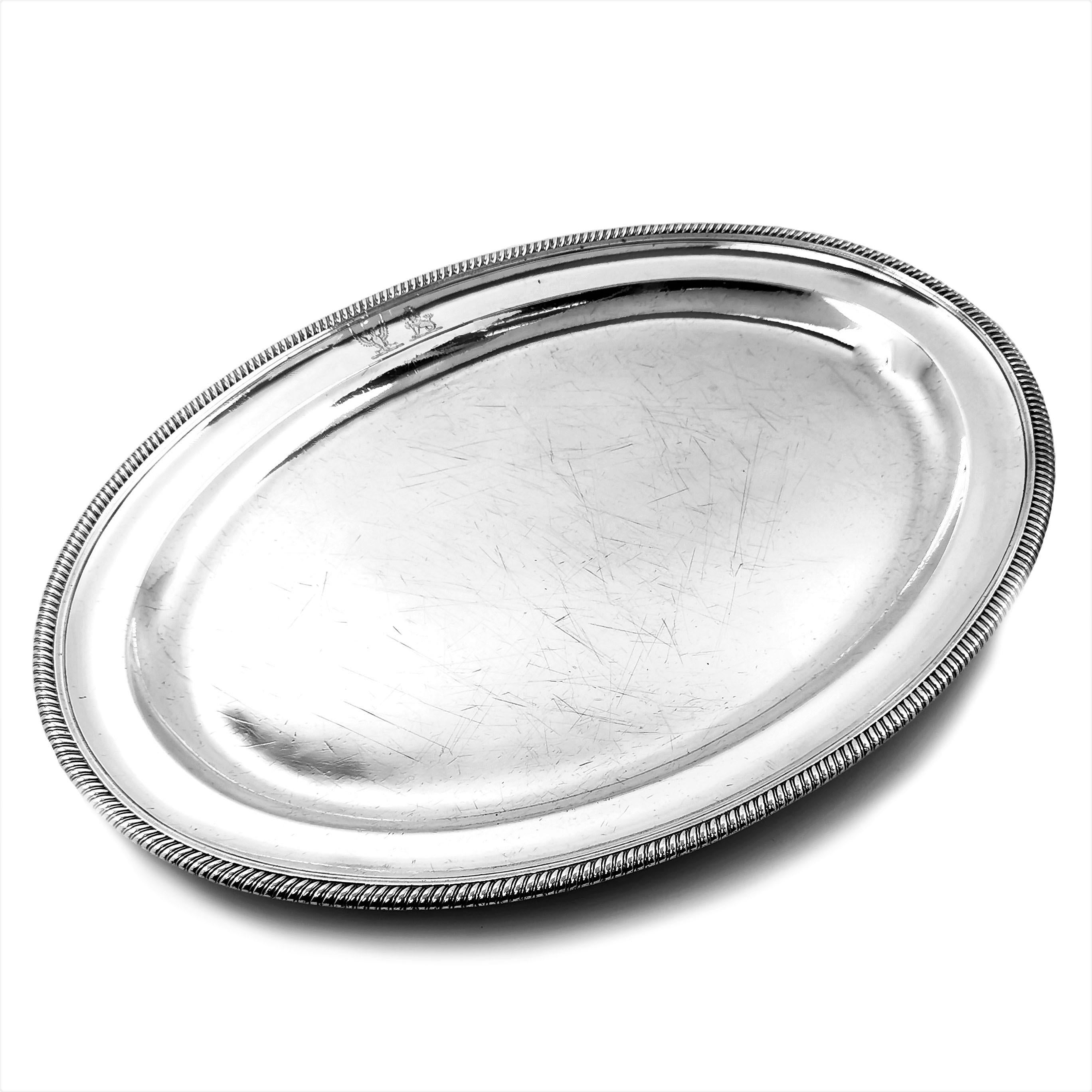 A superb Antique George III solid Silver Serving Platter. This impressive Platter has a classic Georgian oval design with a gadroon pattern border around the rim. The Platter has two engraved crests on the upper rim.

Made in London in 1806 by