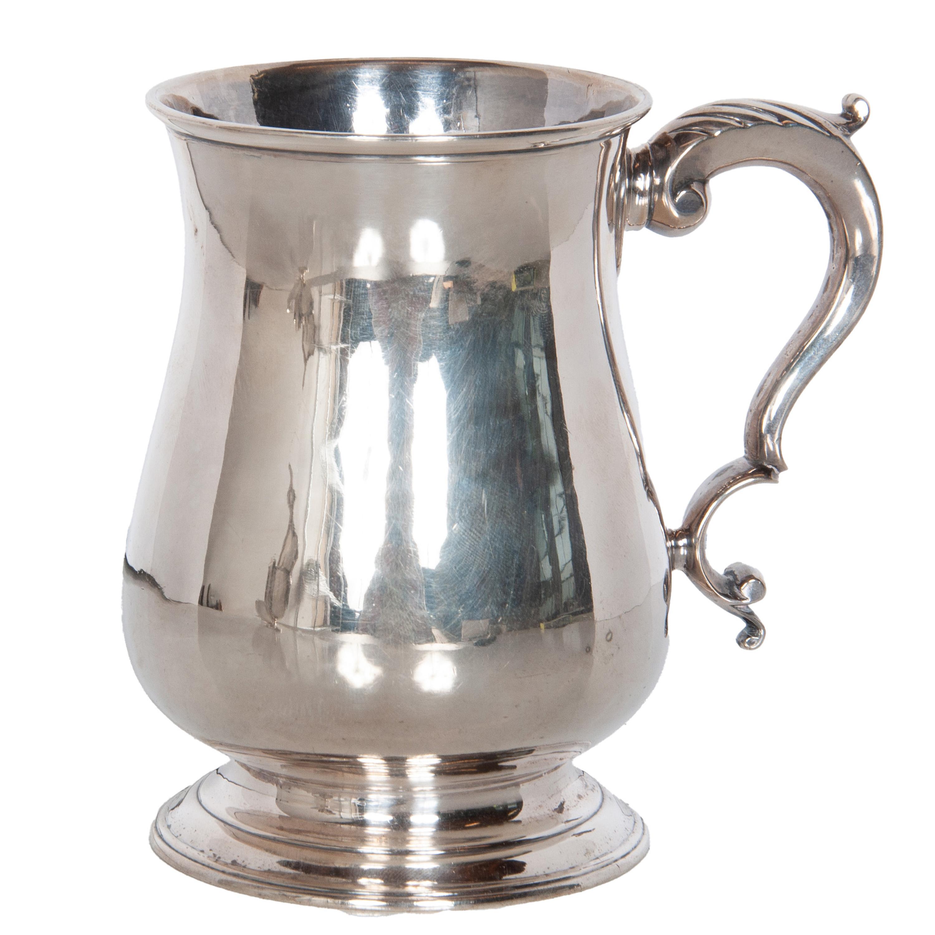 Fina y elegante jarra de pinta de plata de ley de Jorge III, obra de Jacob Marsh, Londres, 1770. 
La jarra tiene una forma de balaustre liso muy agradable, con el borde invertido y elevada sobre un pie extendido escalonado, con doble asa en forma de