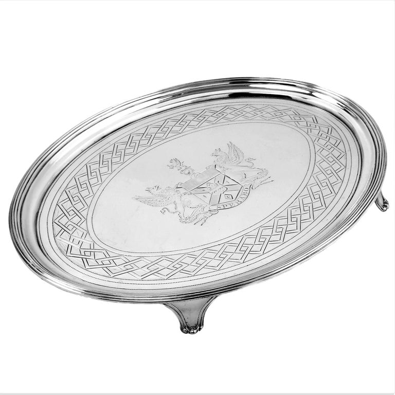 An elegant Antique George III solid Silver Oval Salver with an impressive engraved armorial in the centre and a geometric repeating engraved band around the edge of the Tray. The rim of the Salver has a The Salver stands on four shaped feet.

Made