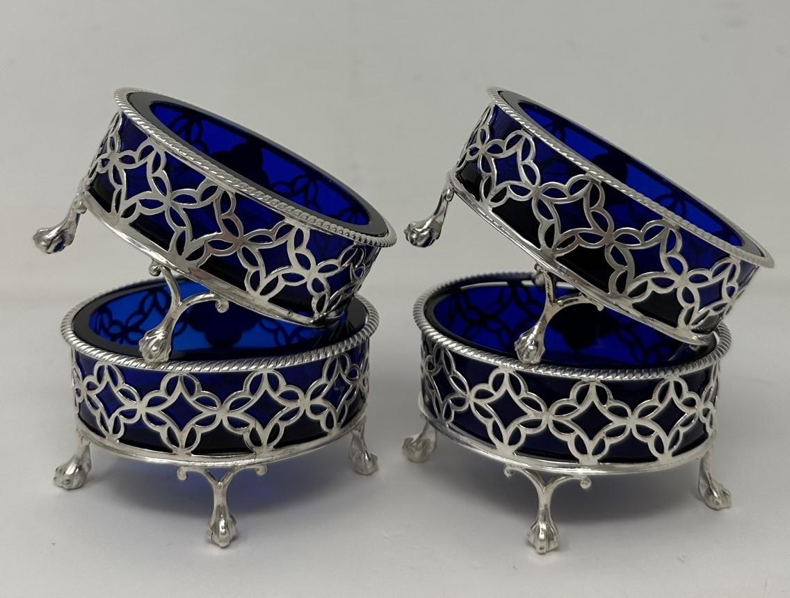 An Outstanding and Rare Museum Quality Identical Set of Four Neo Classical George III third Sterling Silver Table Salts of oval outline raised on four ball and claw supports, complete with their original heavy gauge blue glass liners with seldom
