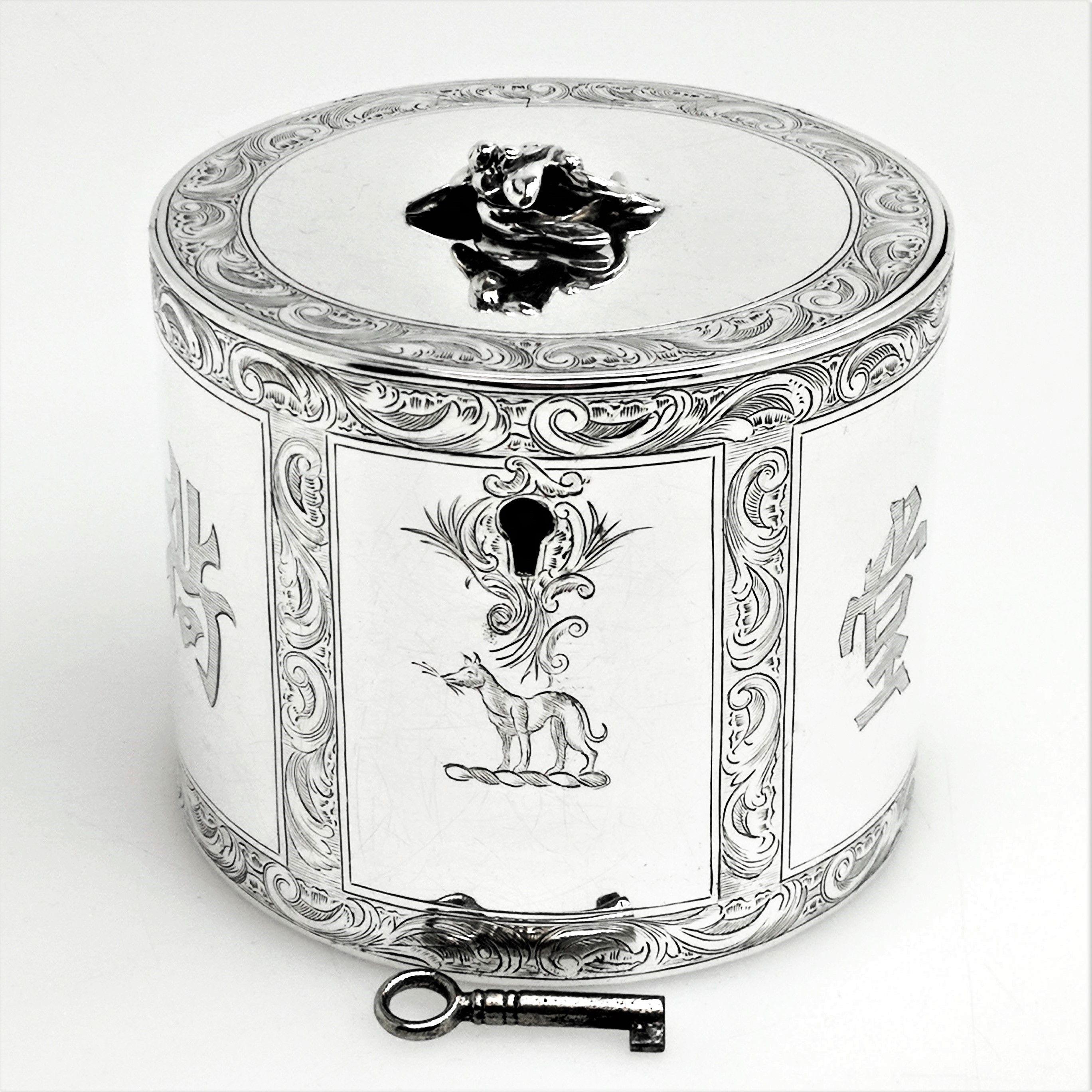 A beautiful Antique George III solid silver tea caddy. This caddy has a circular straight sided can shaped form and is decorated with beautiful and detailed engravings. These engravings form ornate scroll borders created panels on the sides. One of