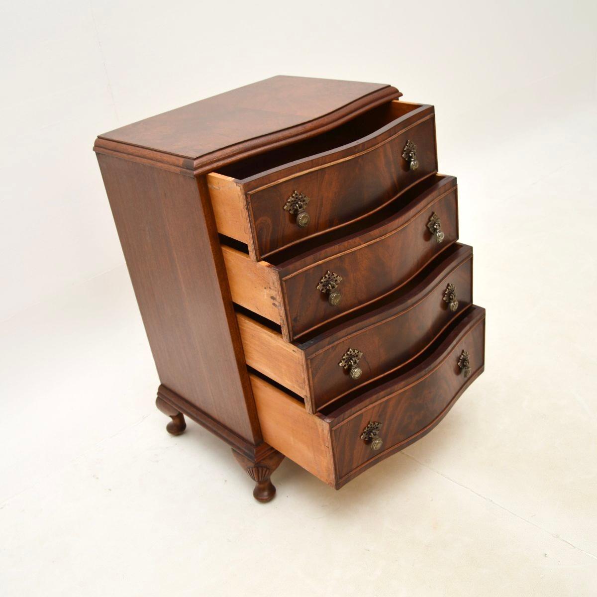 A beautiful antique bedside / side chest of drawers. This was made in England and dates from around the 1950’s.

The quality is superb, this has a serpentine shaped front, sits on cabriole legs with shell carving and has wonderful solid brass
