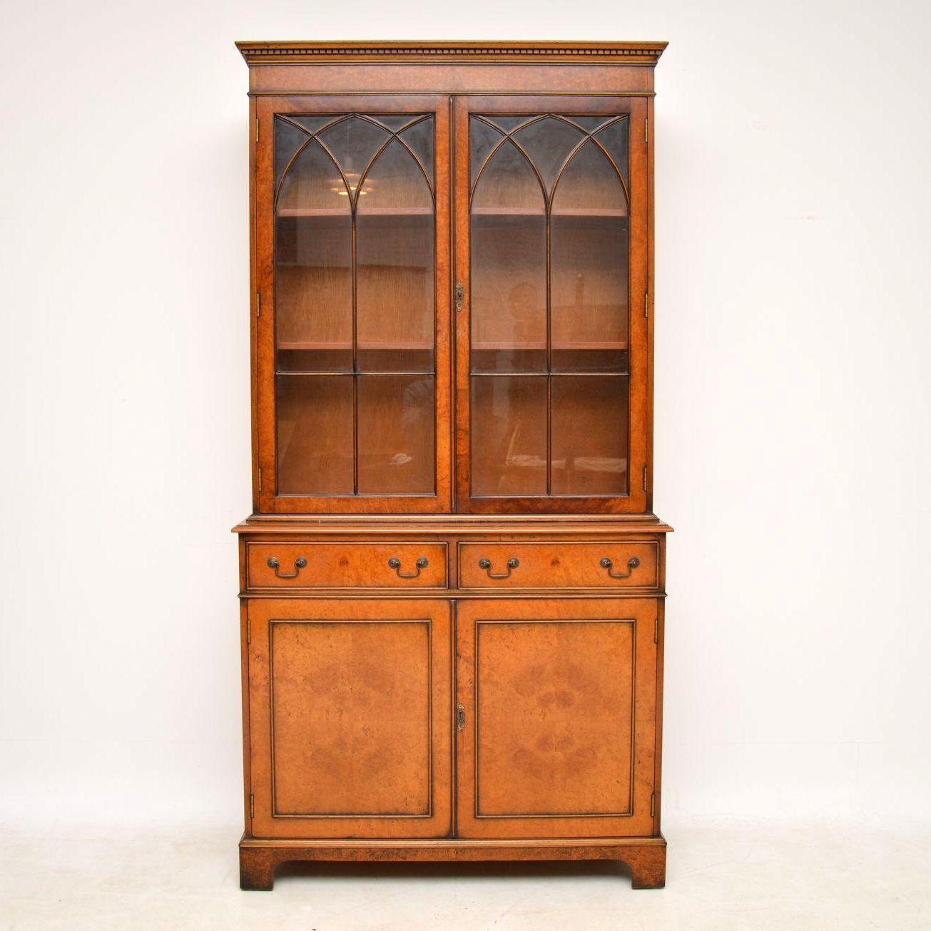 Burr walnut two section bookcase in good original condition, with a lovely mellow color and dating from around the 1950s period. It’s antique Georgian style with a dental moulded cornice, astral glazed top doors, two drawers below and two panelled