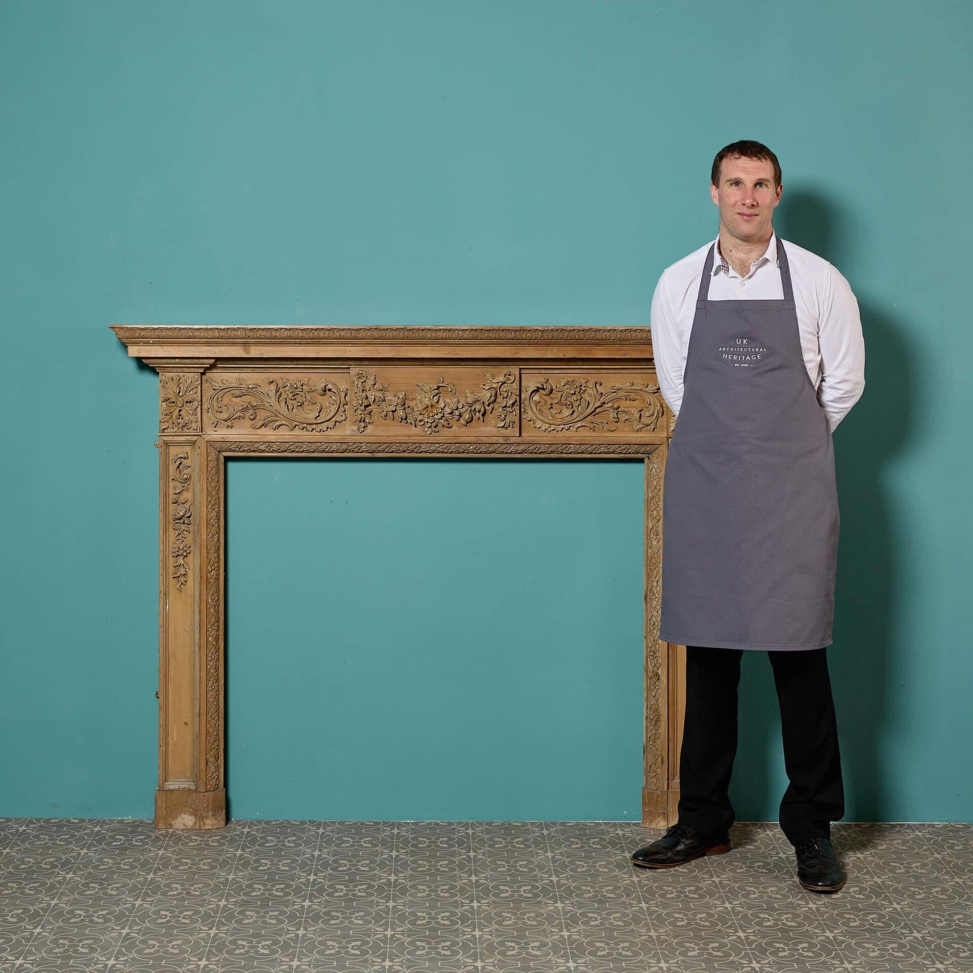 Eine antike geschnitzte Kiefer-Kamineinfassung im georgianischen Stil. Dieser englische Kamin aus der Zeit um 1850 hat eine Oberfläche aus gestripptem Kiefernholz und ist mit vielen Schnitzereien und Blattwerk versehen, die von einem auffallend