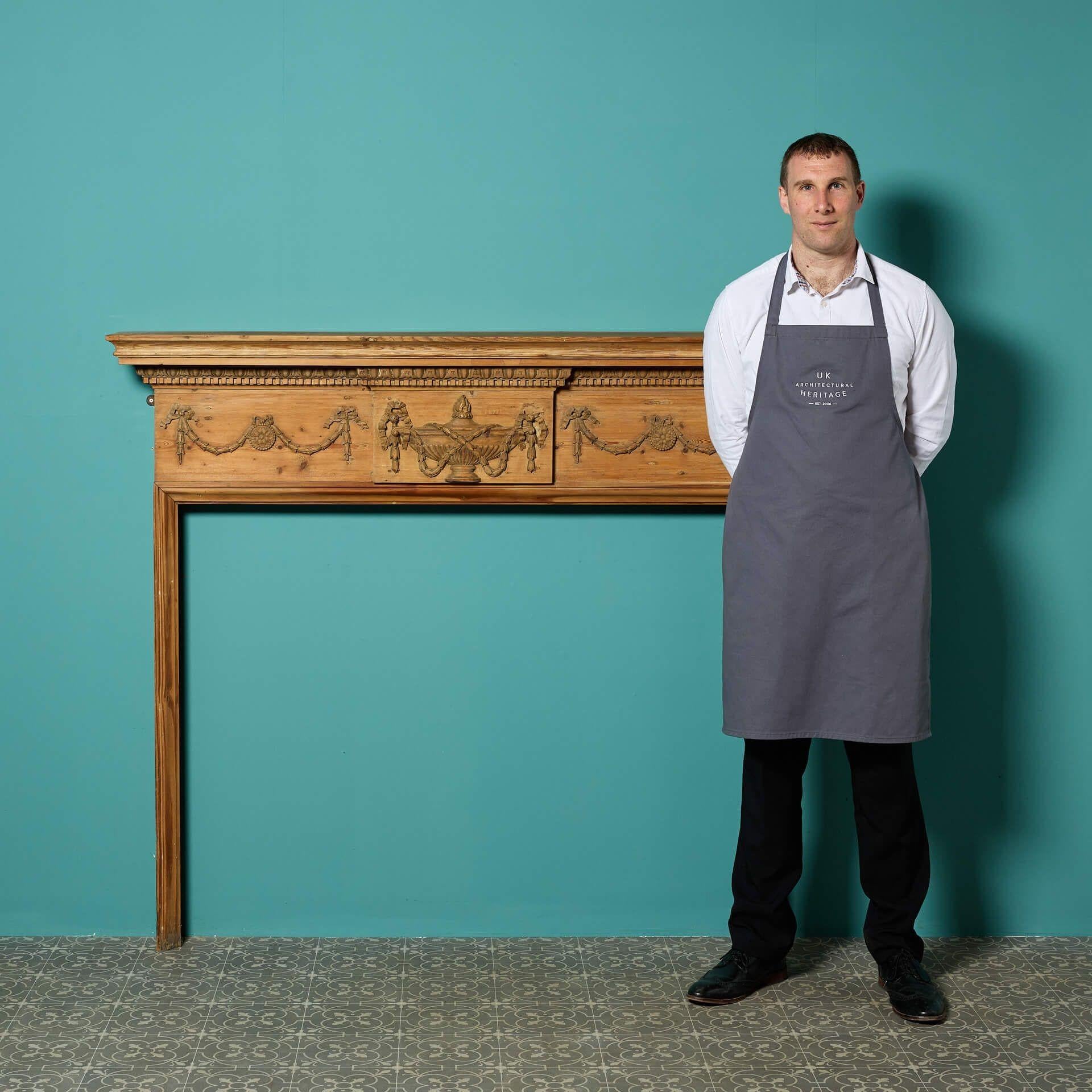 A large antique Georgian style carved pine fire surround, circa 1820.

An English original of the late Regency / Georgian period, this stunning reclaimed fireplace features a carved urn and swag decoration to the frieze below above dentils and egg