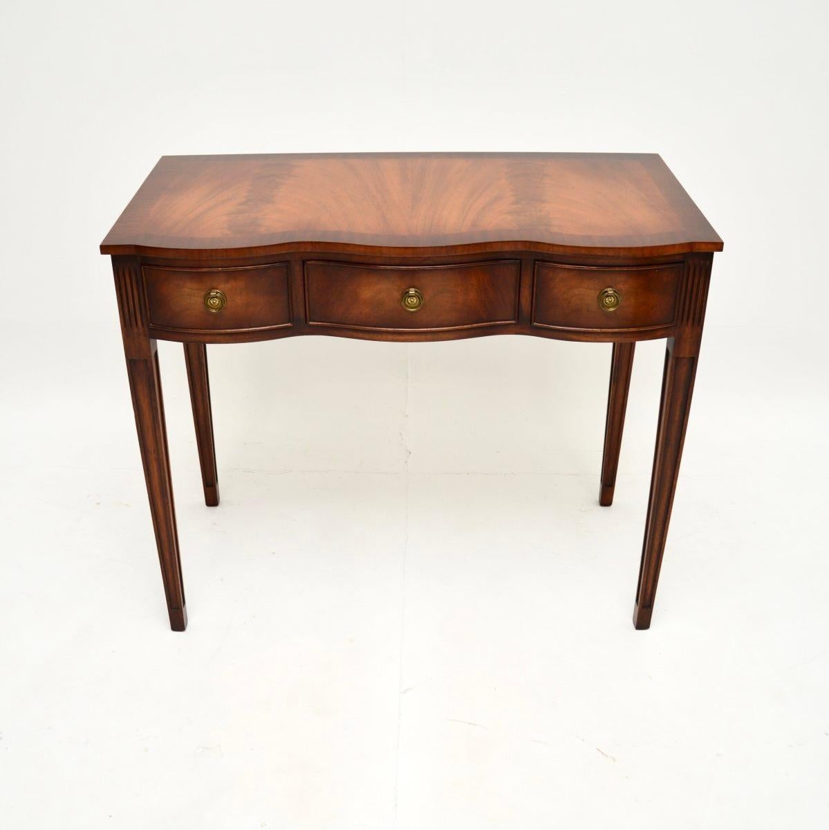A smart and extremely well made antique Georgian style desk / console table. It was made in England, it dates from around the 1950’s.

It is of superb quality and has a lovely design, with a serpentine shaped front standing on tapered and grooved