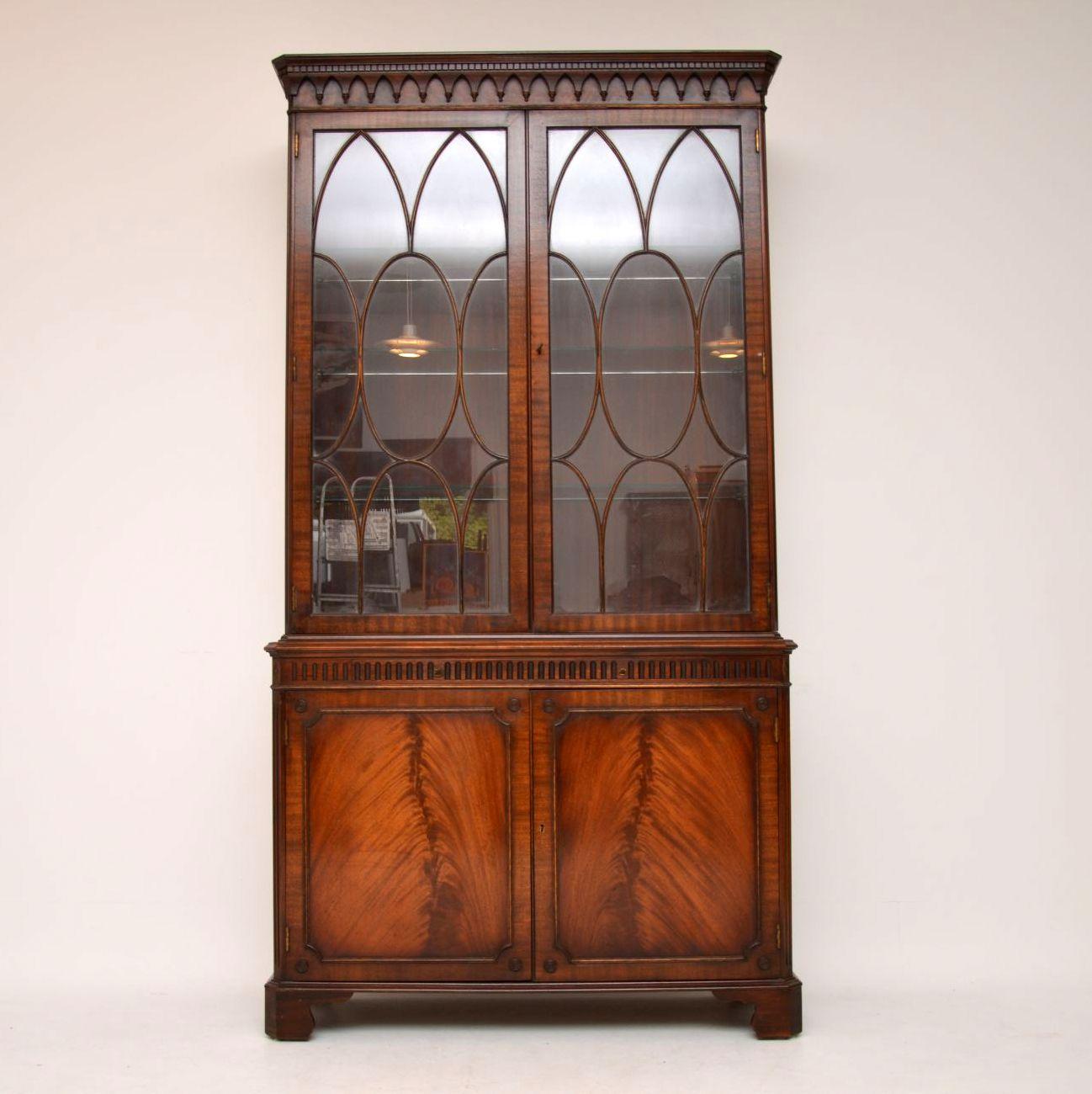 Large antique Georgian style mahogany display cabinet on cupboard dating from circa 1930-1950s period & in excellent condition. This cabinet has a dental cornice, with tear drop mouldings below. The top section has reeded canted corners & fine