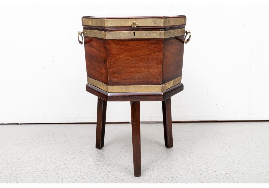 A classic hexagonal shaped Cellarette  in fine flame mahogany. With brass banding and delicately chased brass lift fob and handles  (lacking a key and in inside liner. Raised on three tall square tapering legs. 

Dimensions: H. 27