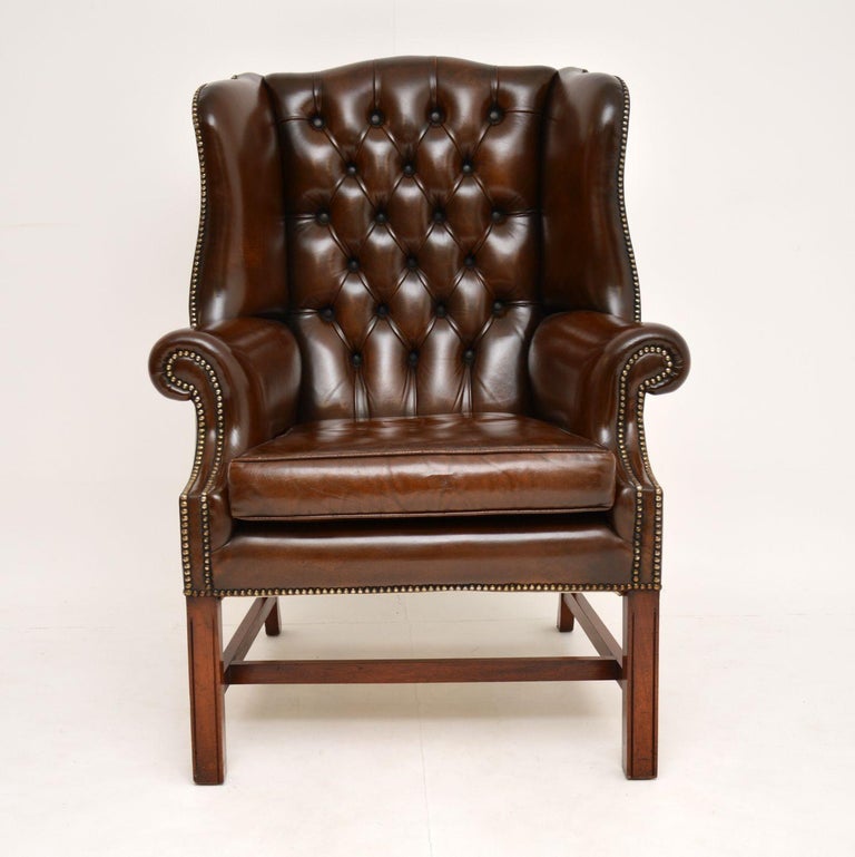 A large and impressive deep buttoned leather wing back armchair, in the antique Georgian Chippendale style. This dates from around the 1950s, and it is of great quality.

It has generous proportions, and is very comfortable, with a hump back, well