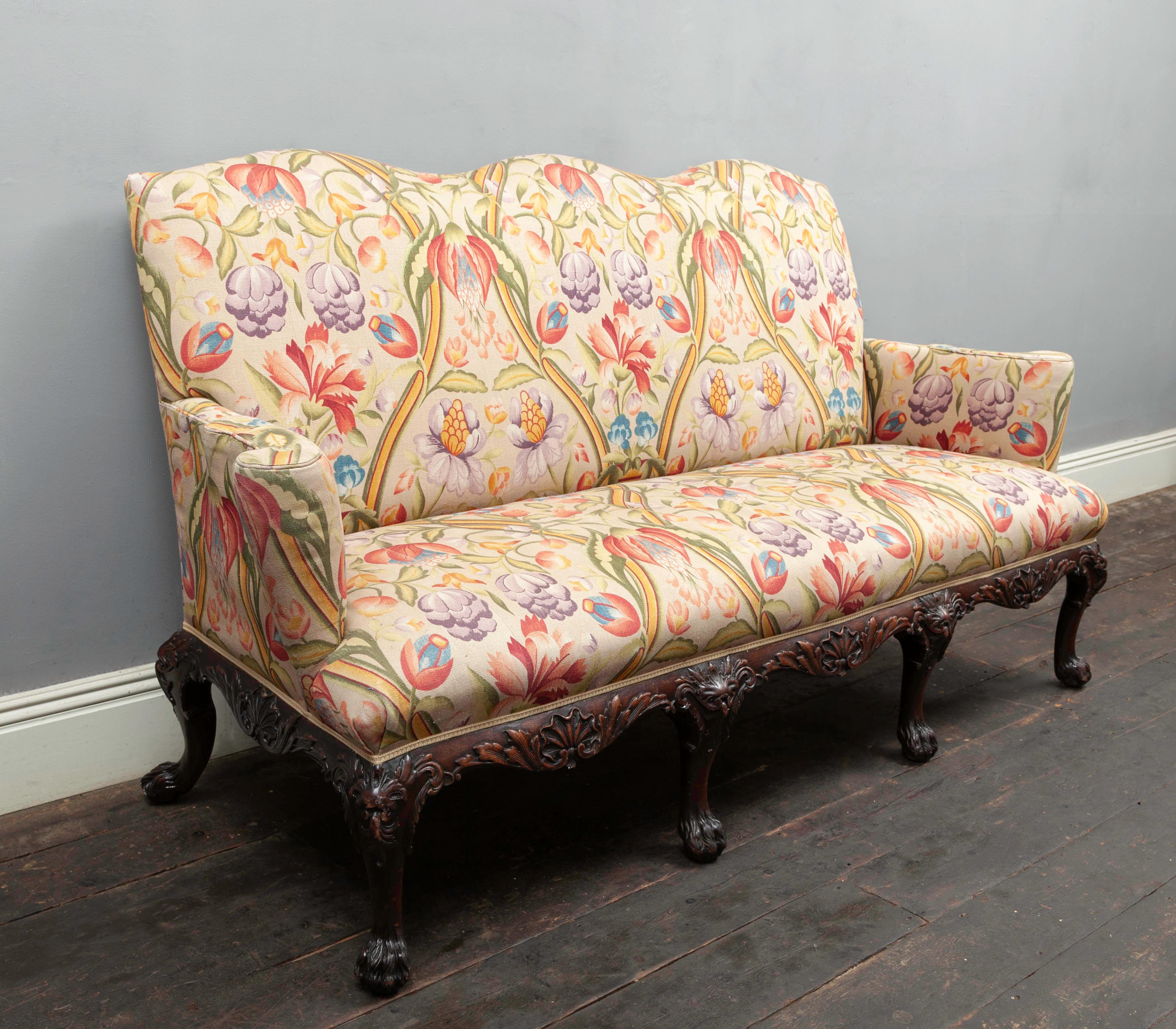 An antique mid-18th century style mahogany settee with later fabric coverings. The serpentine apron is carved with scallop and acanthus decoration, the supporting cabriole legs terminating with ‘hairy paw’ feet.

Upholstered in recent years with a