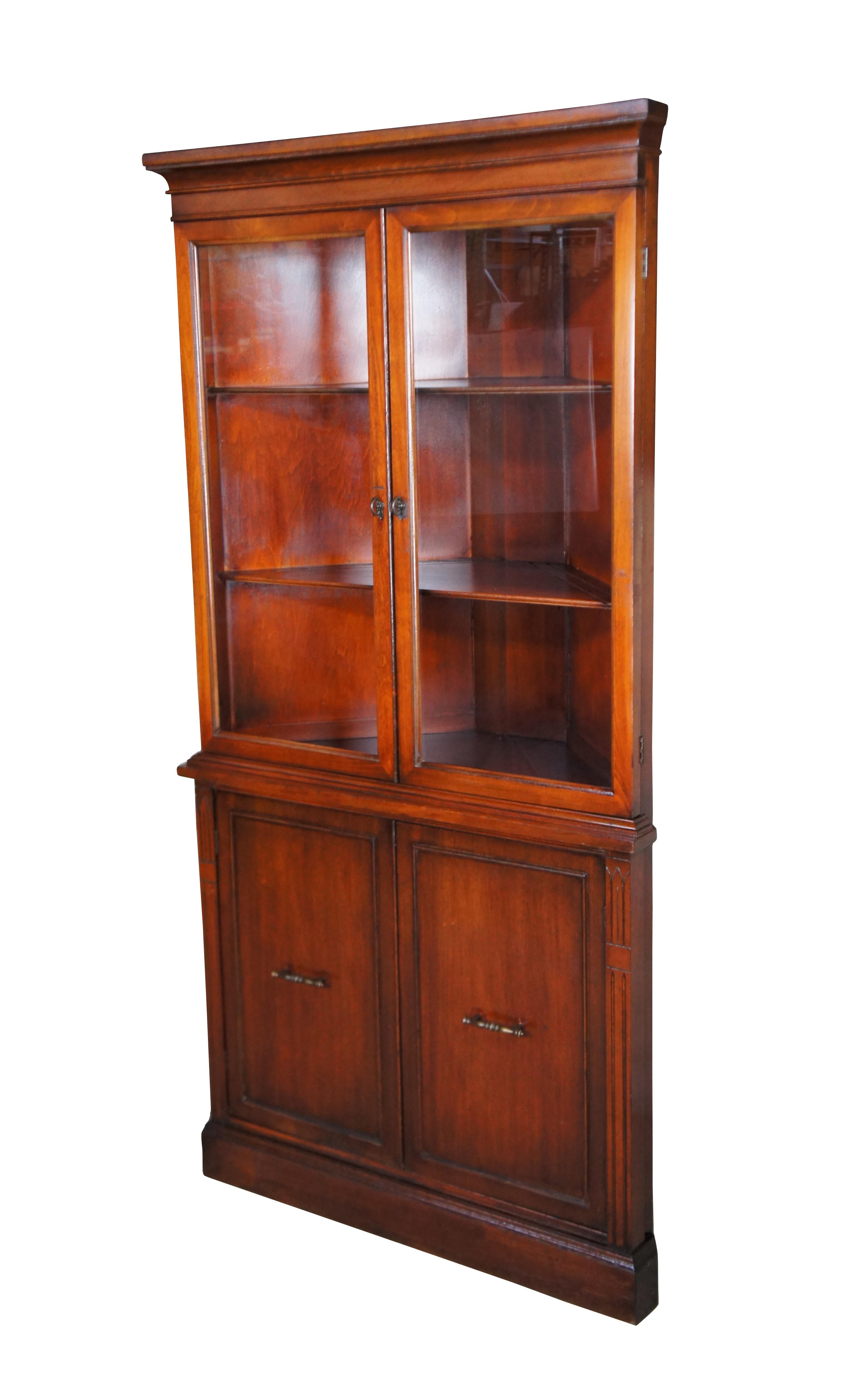 Traditional glass front corner cabinet, c. 1940s.  Features a mahogany case with two glass covered doors along the front.  The cabinet opens to two shelves with plate grooves along the top over a lower cabinet with shelf for accessory storage. 