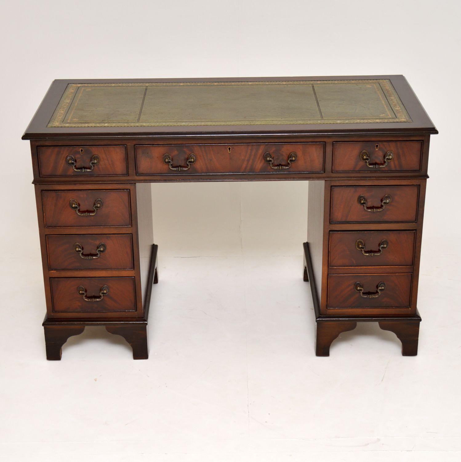 Antique George III style mahogany pedestal desk which is freestanding with a polished back.

It has a tooled leather writing surface, with panelled sides and pedestal backs. The drawer fronts are flame mahogany, with brass handles and locks on the