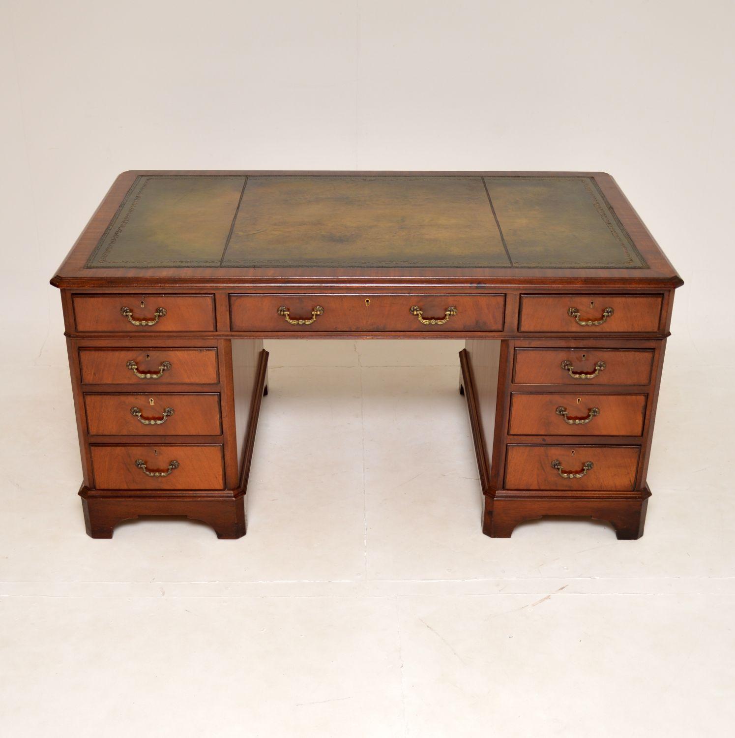A large and impressive antique pedestal desk in the Georgian style. This was made in England, it dates from around the 1950’s.

It is of excellent quality, with a beautiful inset green leather top that has been hand coloured and gold tooled. The