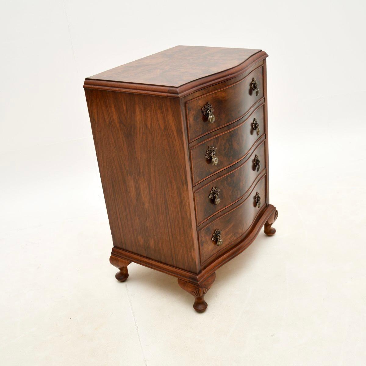A beautiful antique walnut bedside / side chest of drawers. This was made in England and dates from around the 1950’s.

The quality is superb, this has a serpentine shaped front, sits on cabriole legs with shell carving and has wonderful solid brass