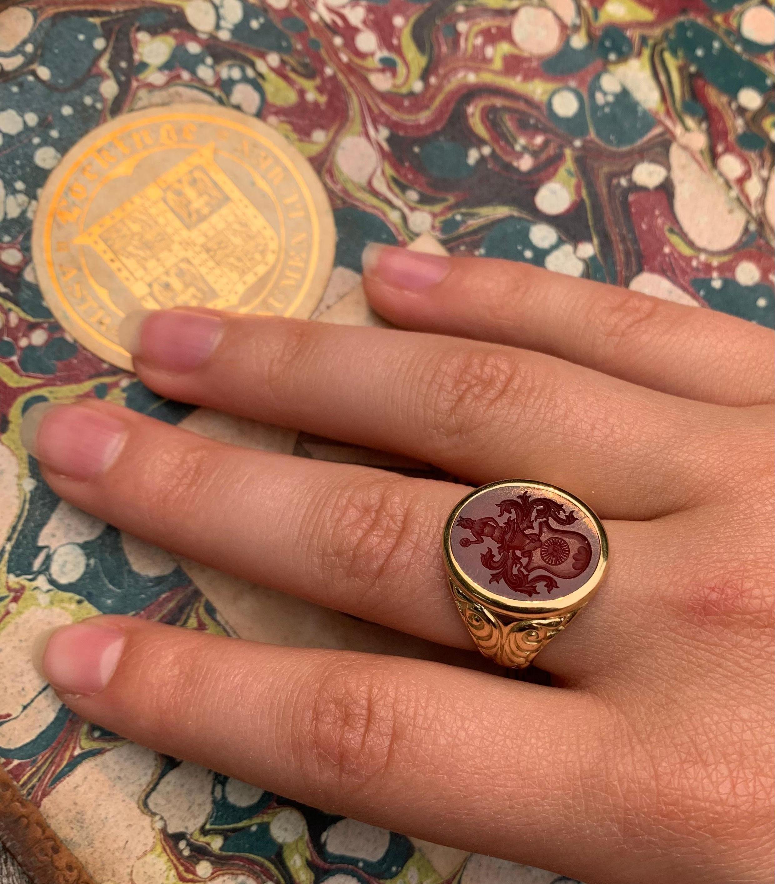 Fine large antique 14K yellow gold and carnelian Sun in Splendour intaglio Georgian signet ring 
Early 19th Century
Superbly carved oval carnelian intaglio of an ornate heraldic crest with a central shield shaped coat of arms depicting a human face