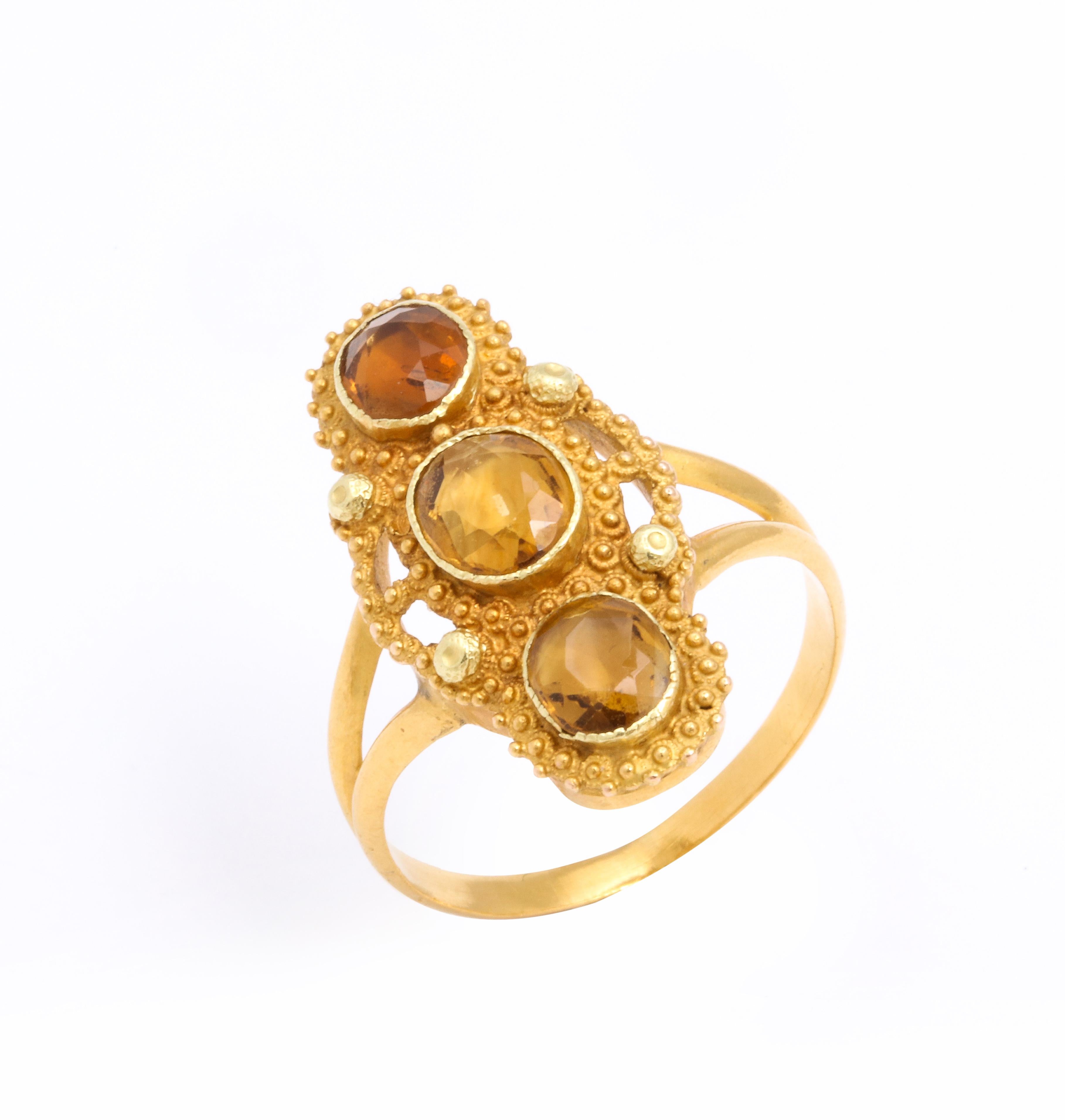 Drei ovale Topas-Edelsteine sind in diesem georgischen Ring vertikal in 18-karätiges Gold gefasst. Die Edelsteine sehen aus, als wären sie wie Honigtropfen auf dieser Fassung mit drei Steinen aufgespießt. Hervorragende Goldarbeit zeichnet sich in
