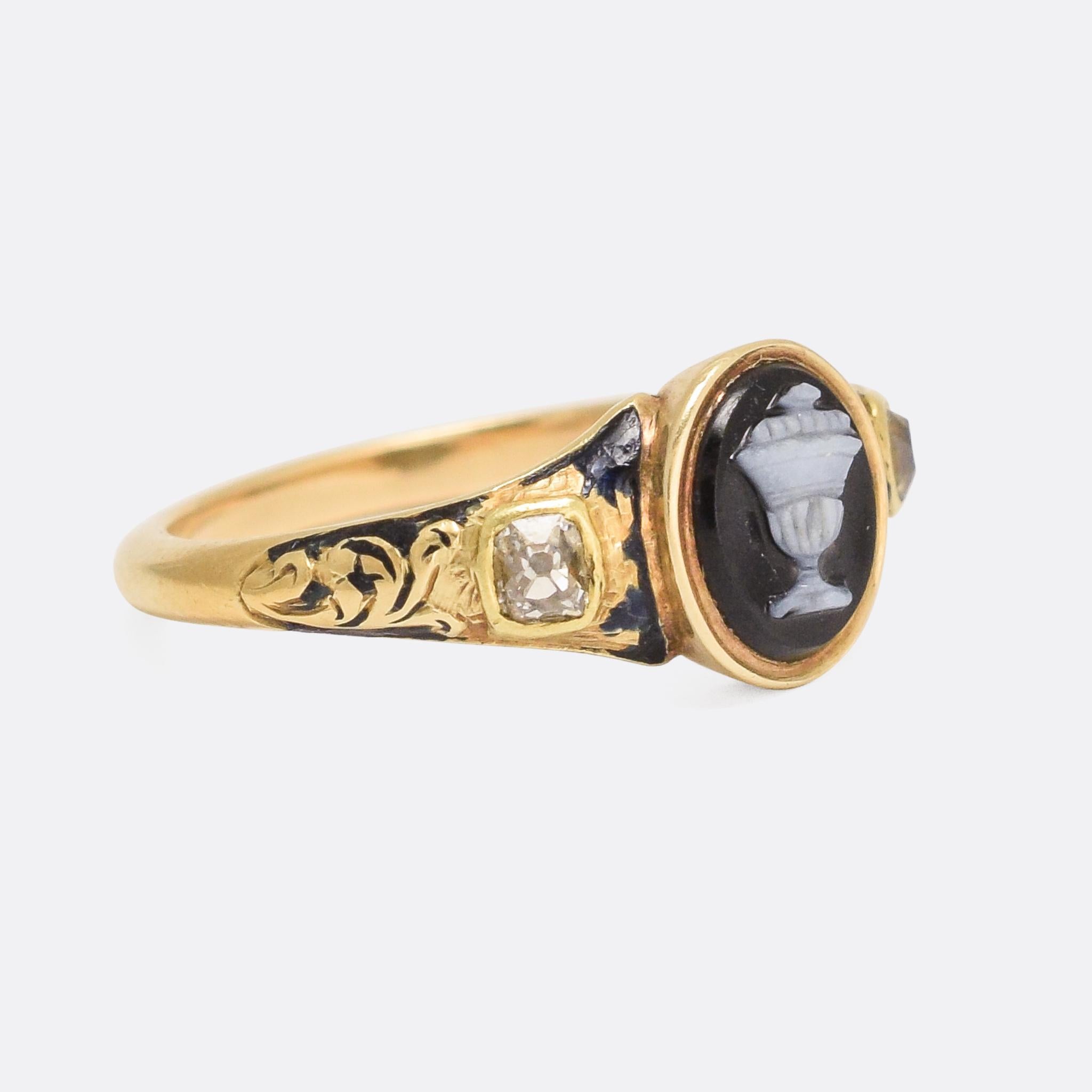 An exceptional Georgian mourning ring with an Urn onyx cameo centrepiece, old mine cut diamond shoulder accents, and an oval locket compartment hidden behind the head. The shoulders also feature fine foliate detailing, and, quite remarkably given