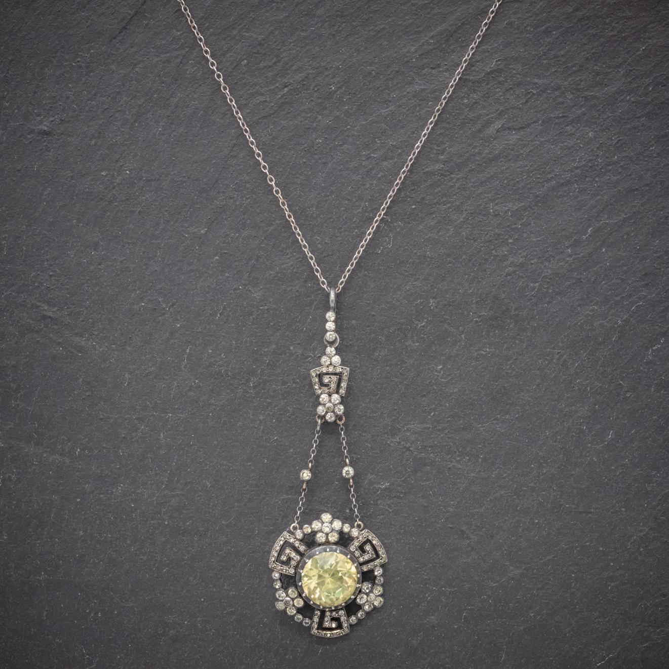 A glamorous antique necklace featuring a fabulous floral drop pendant suspended from chains. The pendant is decorated with sparkling white Paste Stones with a larger 5ct Paste in the centre that shines with a bright golden glow similar to that of a