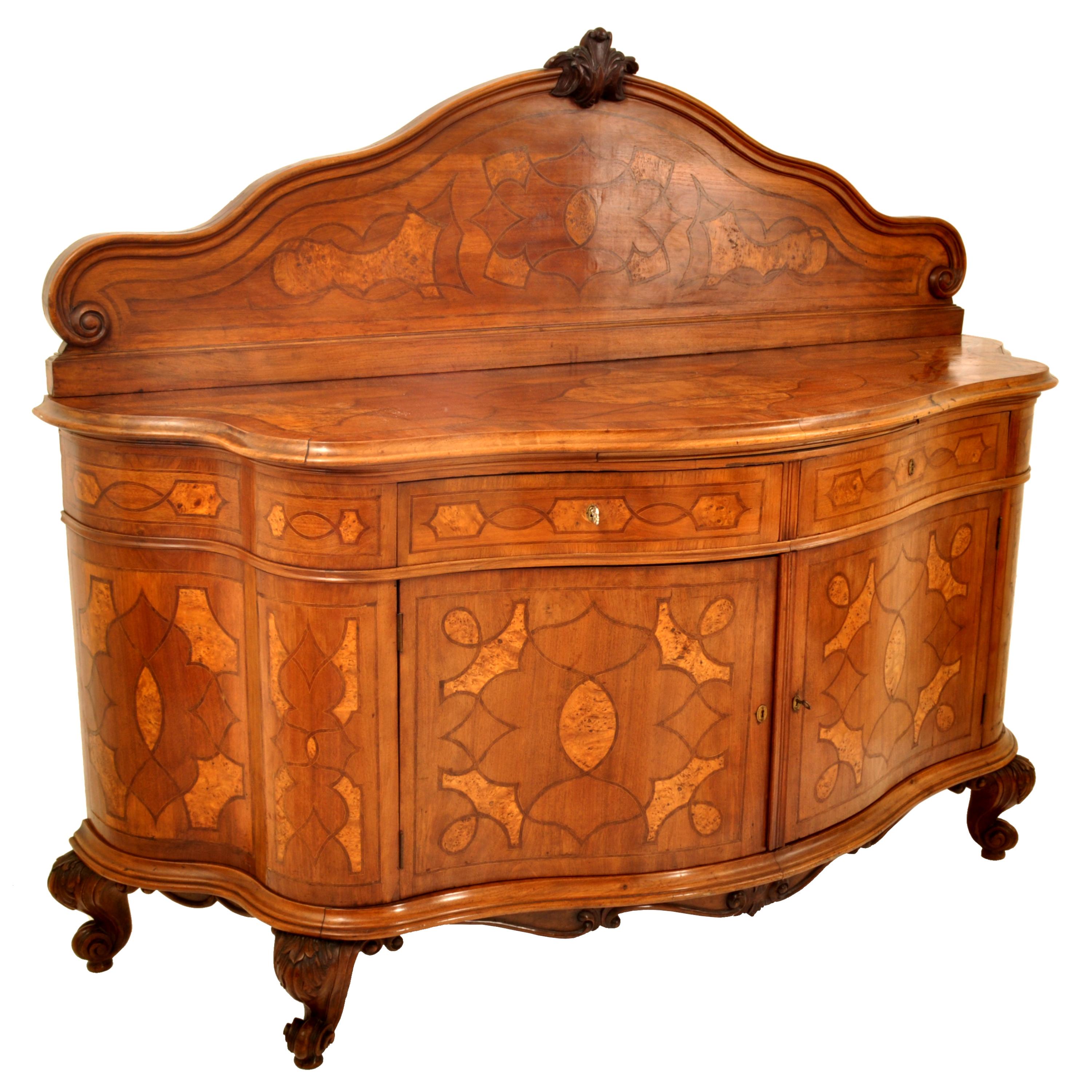 A majestic inlaid antique walnut with marquetry fruitwood inlaid Austrian buffet in the Baroque taste, circa 1890.
The sideboard of serpentine shape and having a carved and inlaid marquetry back, the back having a carved scrolled crest to the top