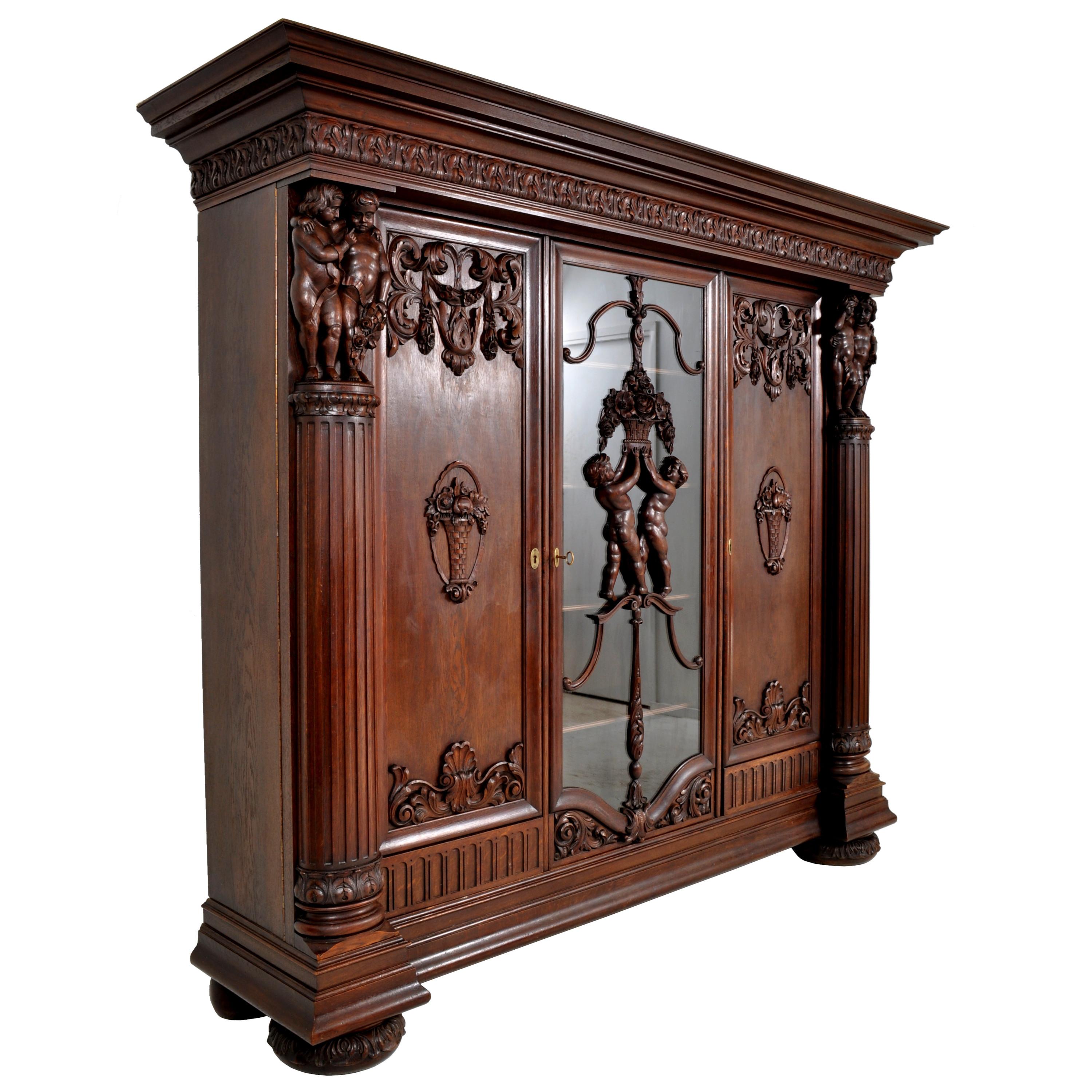 A fabulous antique German Baroque Revival carved oak library cabinet or bookcase, circa 1890. The cabinet is very finely carved with an allegory of love, represented by six carved putti in different poses. The cabinet having a stepped crown with a