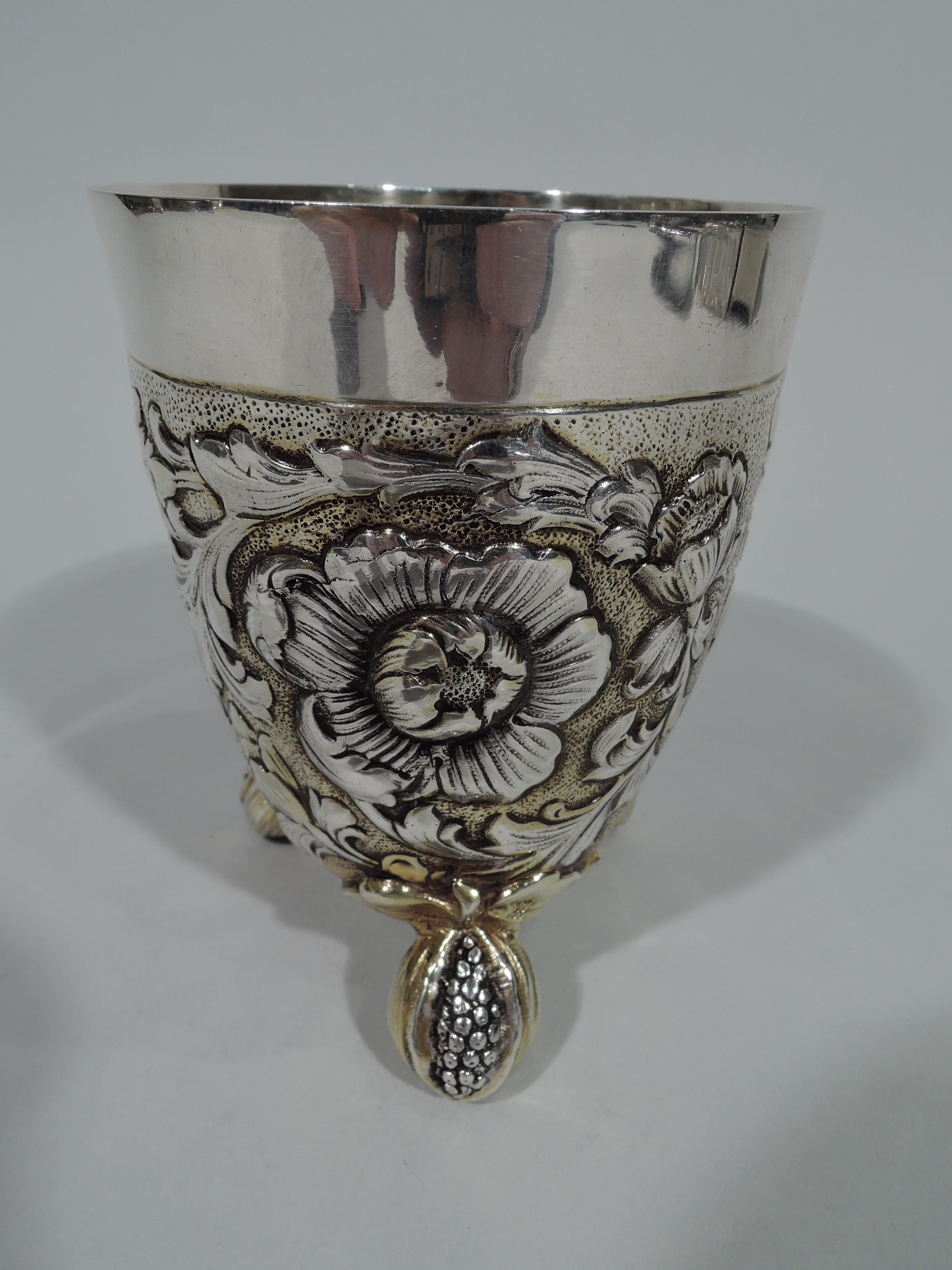 German Baroque-style parcel gilt 800 silver beaker, circa 1900. Tapering sides and curved bottom with 3 leaf-mounted pomegranate supports bursting with seeds. Chased and fluid rinceaux floral ornament on stippled ground. Interior gilt. Hallmarked.
