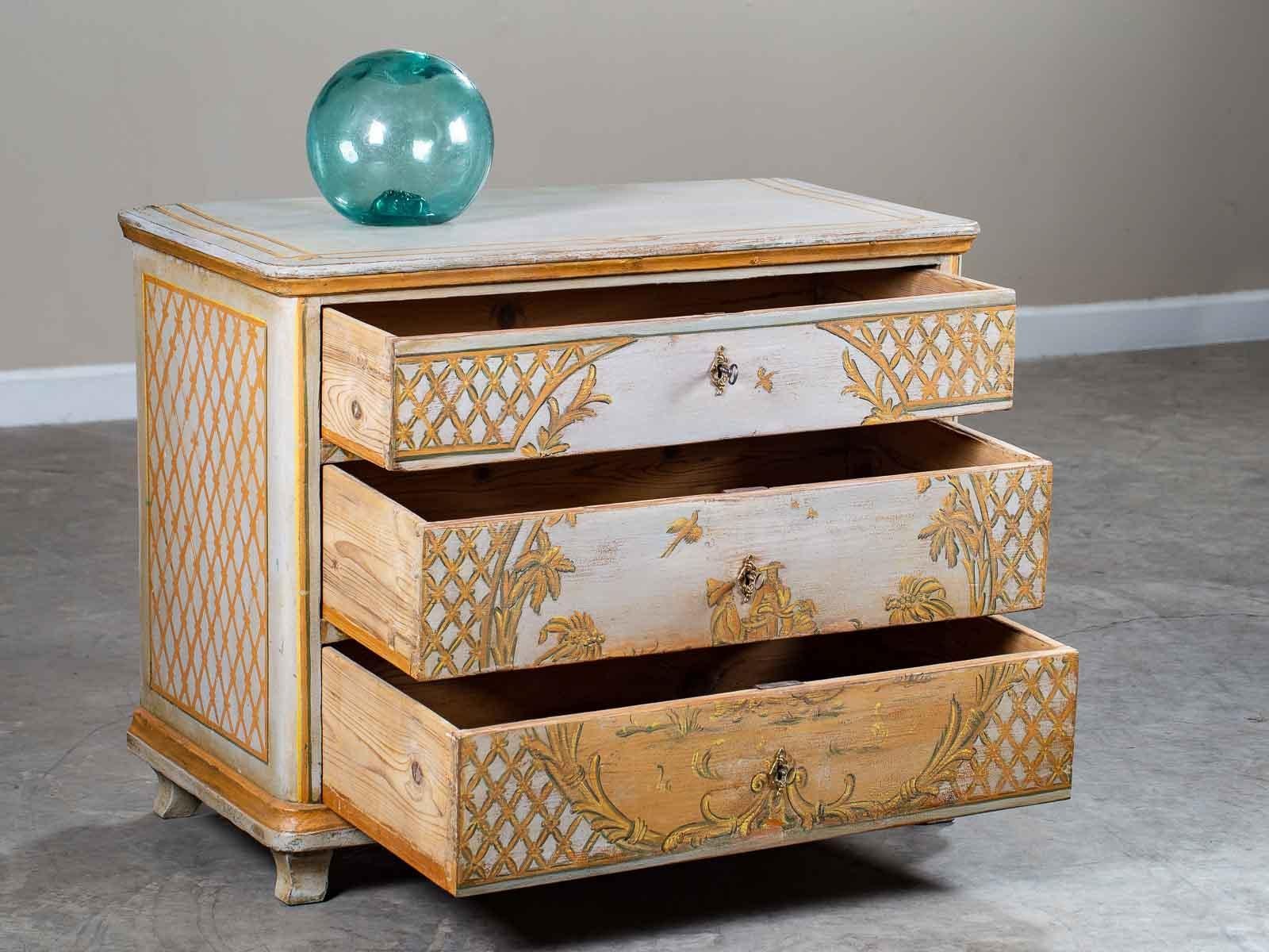 A charming antique German Biedermeier painted chest of drawers, circa 1830. The handsome Rococo design of the refreshed painted finish features a hand-painted design of trellis pattern on each side while on the front the trellis frames the central