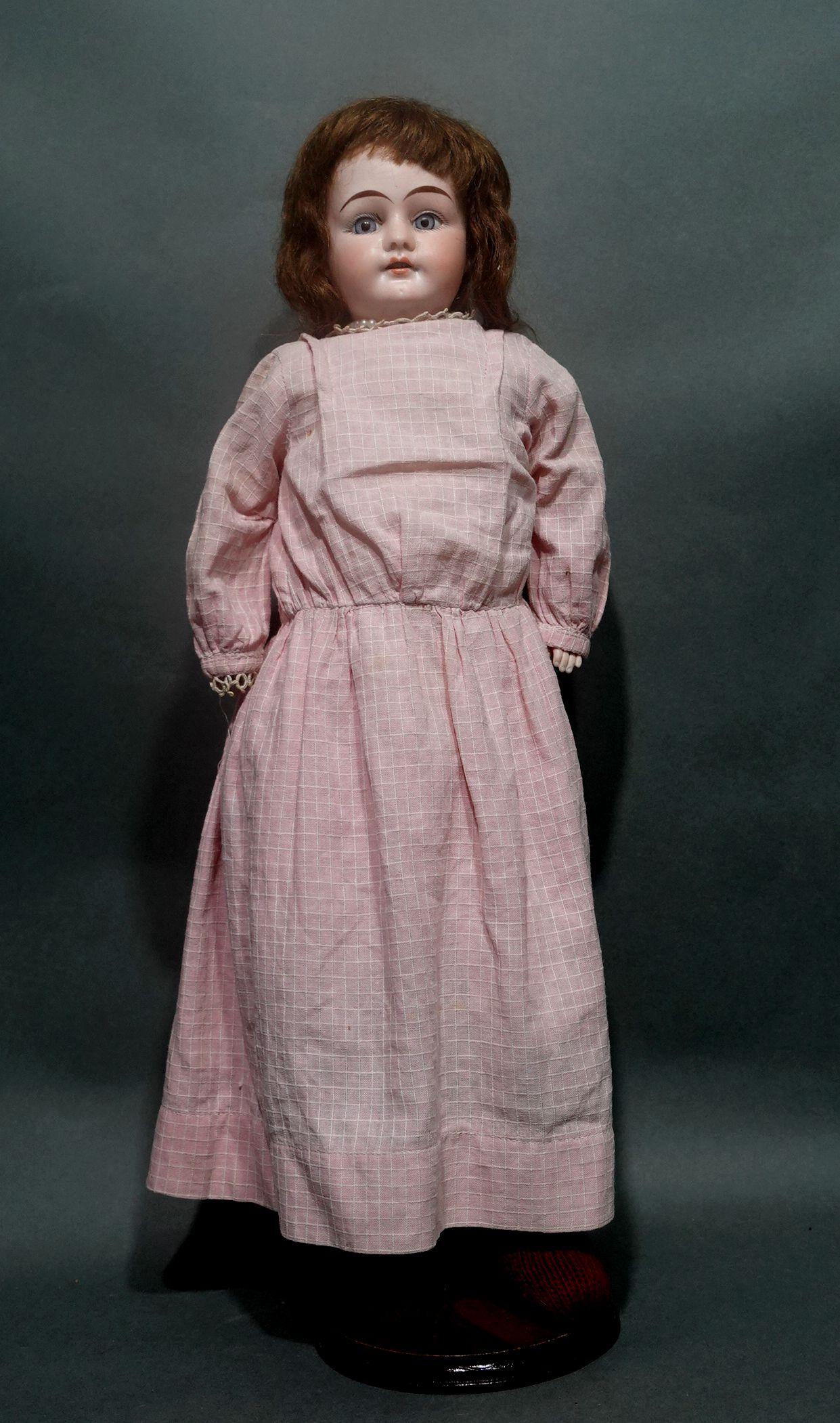 An original Armand Marseille doll, with a Bisque head and hands. Her feet wear red socks. Beautiful blue glass-fixed eyes and her parted lips show her perfect little teeth. Great overall condition. She is wearing a pink cotton dress, white