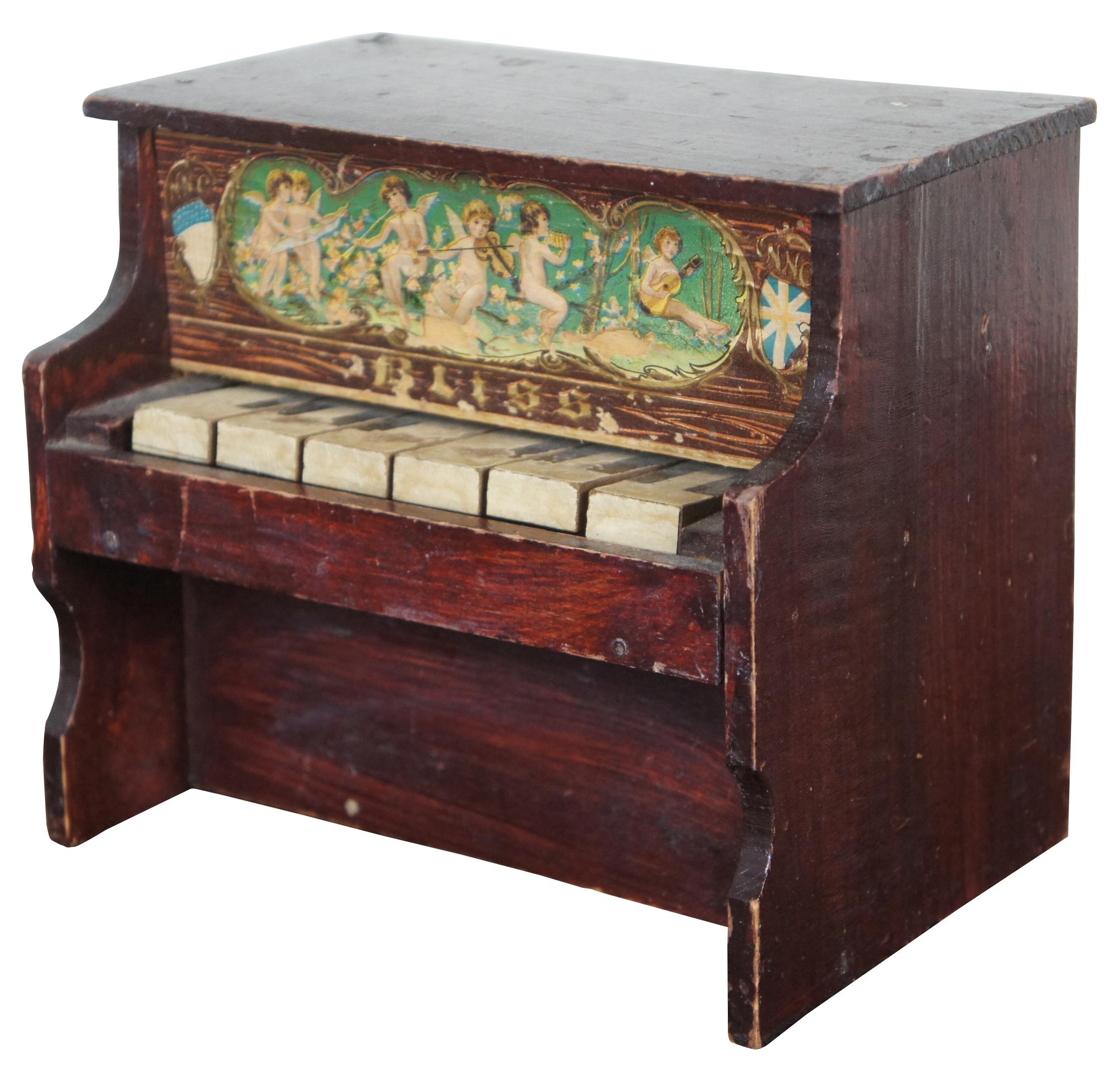 Antique German Bliss toy piano with a six note glockenspiel and lithograph image of cherubs playing instruments. Measure: 7