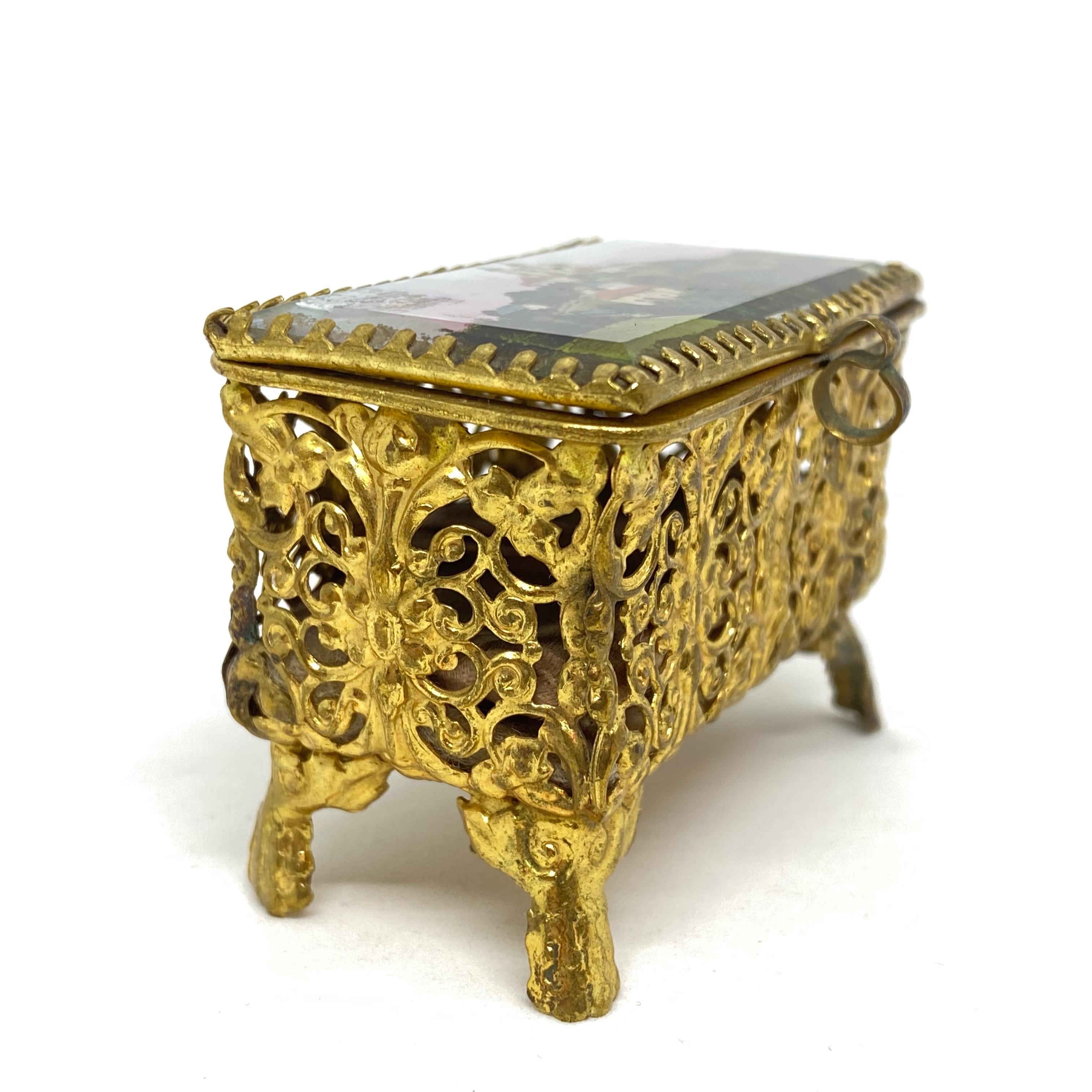 A gorgeous glass trinket box with some ormolu adornments. The hinged top featuring a City view of a Church or Castle. No restoration has been carried out on this charming little trinket box, which remains in very stabile and functioning condition,