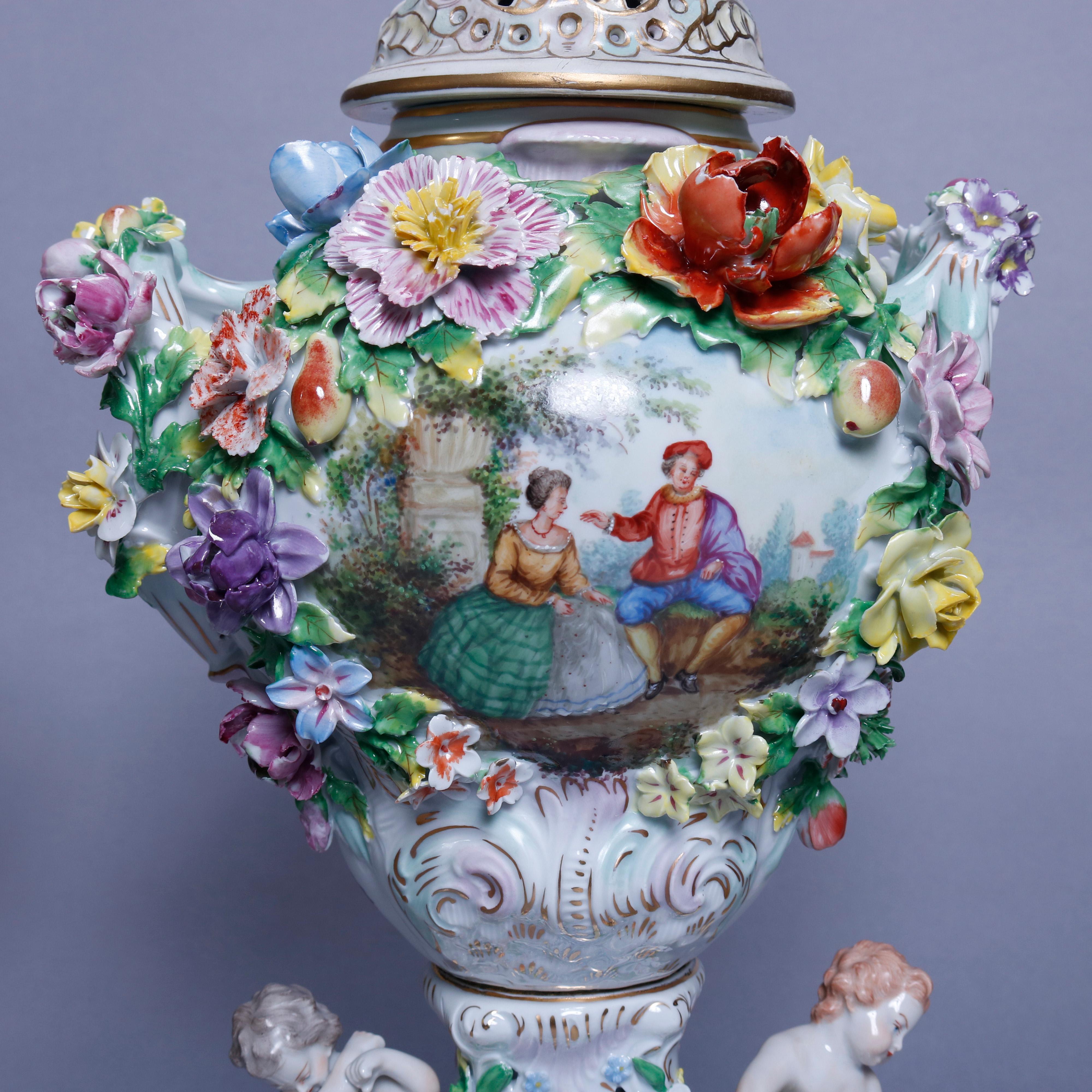 An antique pair of classical German Dresden porcelain urns each offer central hand painted reserve depicting courting scenes in countryside setting, en verso floral reserve, overall applied flowers, raised on pierced plinth with garden flowers and