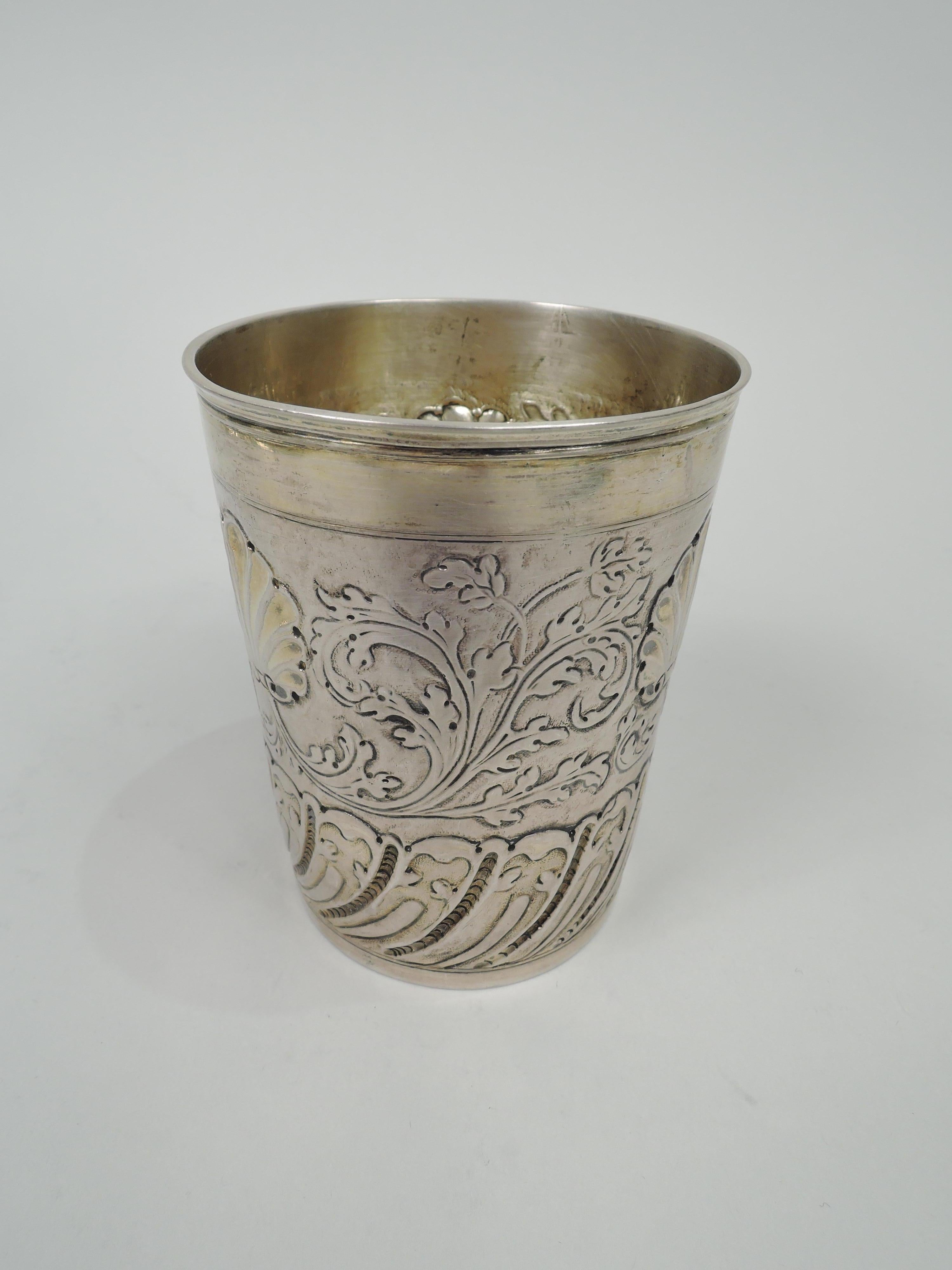 German Classical silver beaker cup, 18th century. At top leafing scrollwork and scallop shells; at bottom twisted leaf-and dart border. Ornament chased and heightened with engraving. Interior gilt washed. Maker’s mark comprising letters S and I.