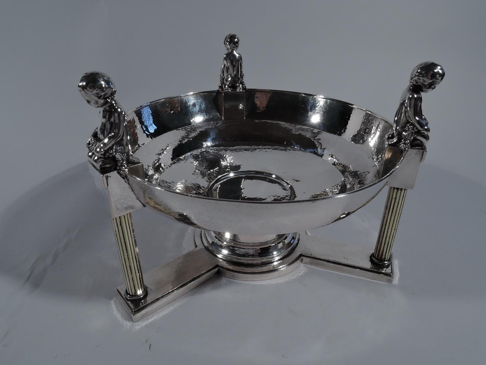 Classical hand-hammered 800 silver centerpiece bowl, circa 1910. Round and stepped on short columnar shaft mounted to stepped circular tripartite base, each with fluted column supporting rectilinear pedestal overlapping bowl rim. Each pedestal has