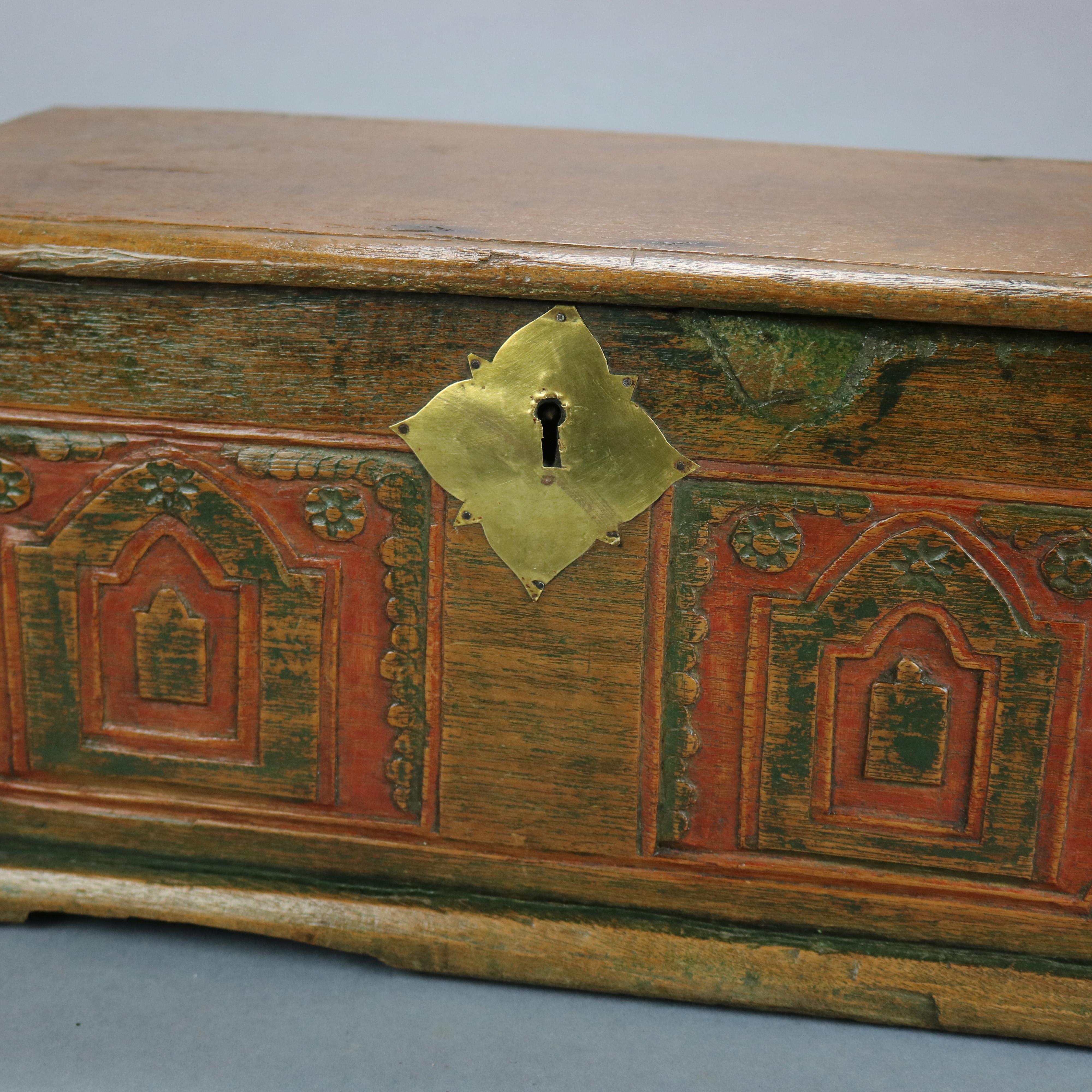 An antique German miniature blanket chest offers lift top having hand wrought strap hinges over box with hand cut dovetails and front having double carved and polychromed reserves, sides with iron handles, interior with patch box, 18th
