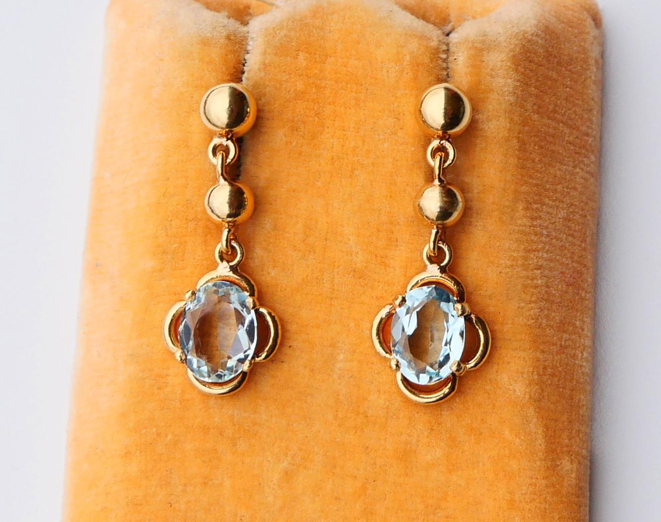 A  pair of shiny oval cut Aquamarines framed in flower bezels. All parts in solid 18K Yellow Gold. German pair, created ca. 1920s-  1930s. Hallmarked with maker's logo and 750. Intricate screws, very popular at that time.

Aquamarines of light Blue