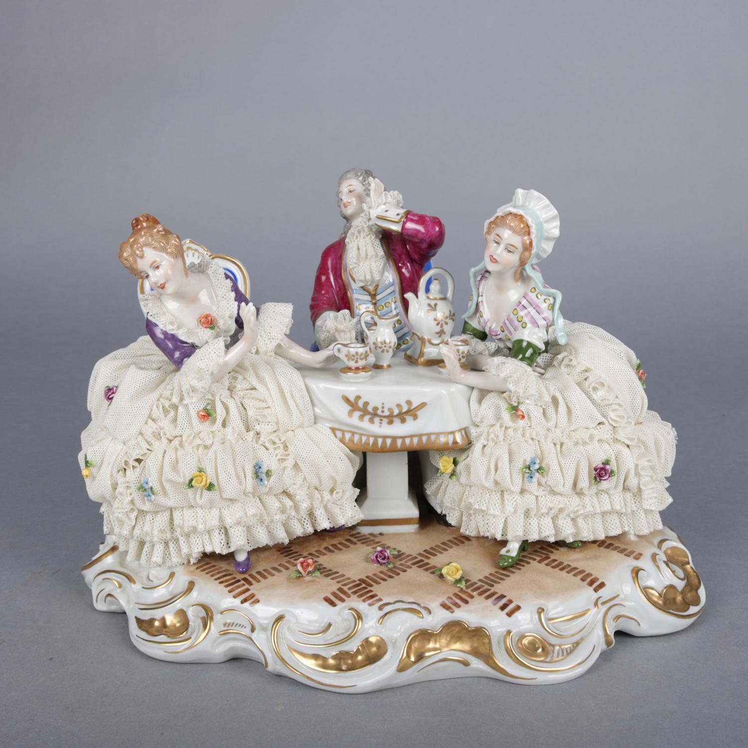 An antique German Dresden lace grouping by Unter Weiss Bach features hand painted figural porcelain parlor scene with two ladies and a gentleman caller at tea table, gilt highlights throughout, crown mark on base, 19th century

Measures: 8