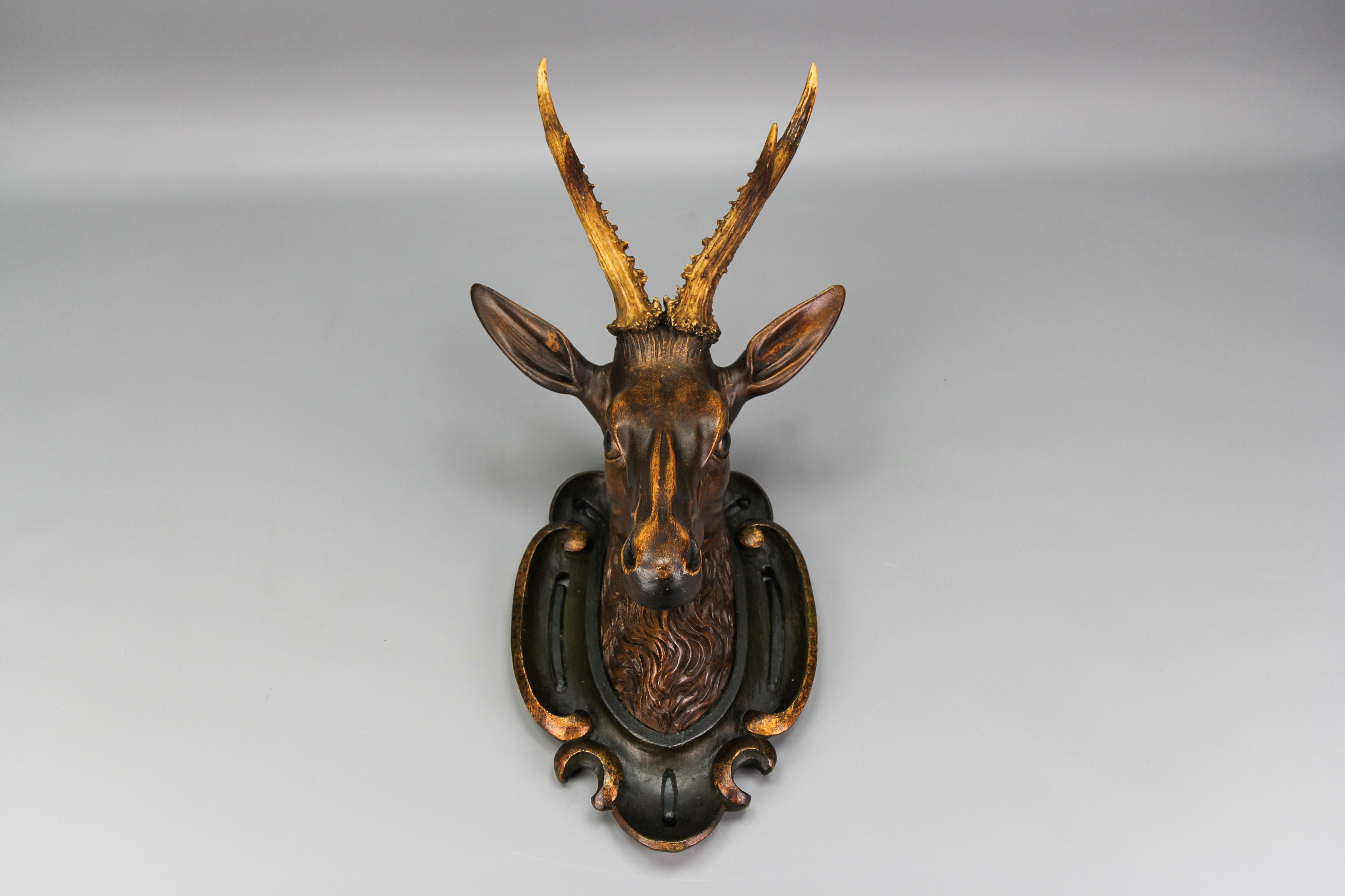 19th-century Baroque-style German hand-carved wooden deer head on a carved and hand-painted wall plaque.
An impressive antique hand-carved wall-hanging deer head made of linden wood with genuine antlers mounted on a carved oval ornate wooden plaque