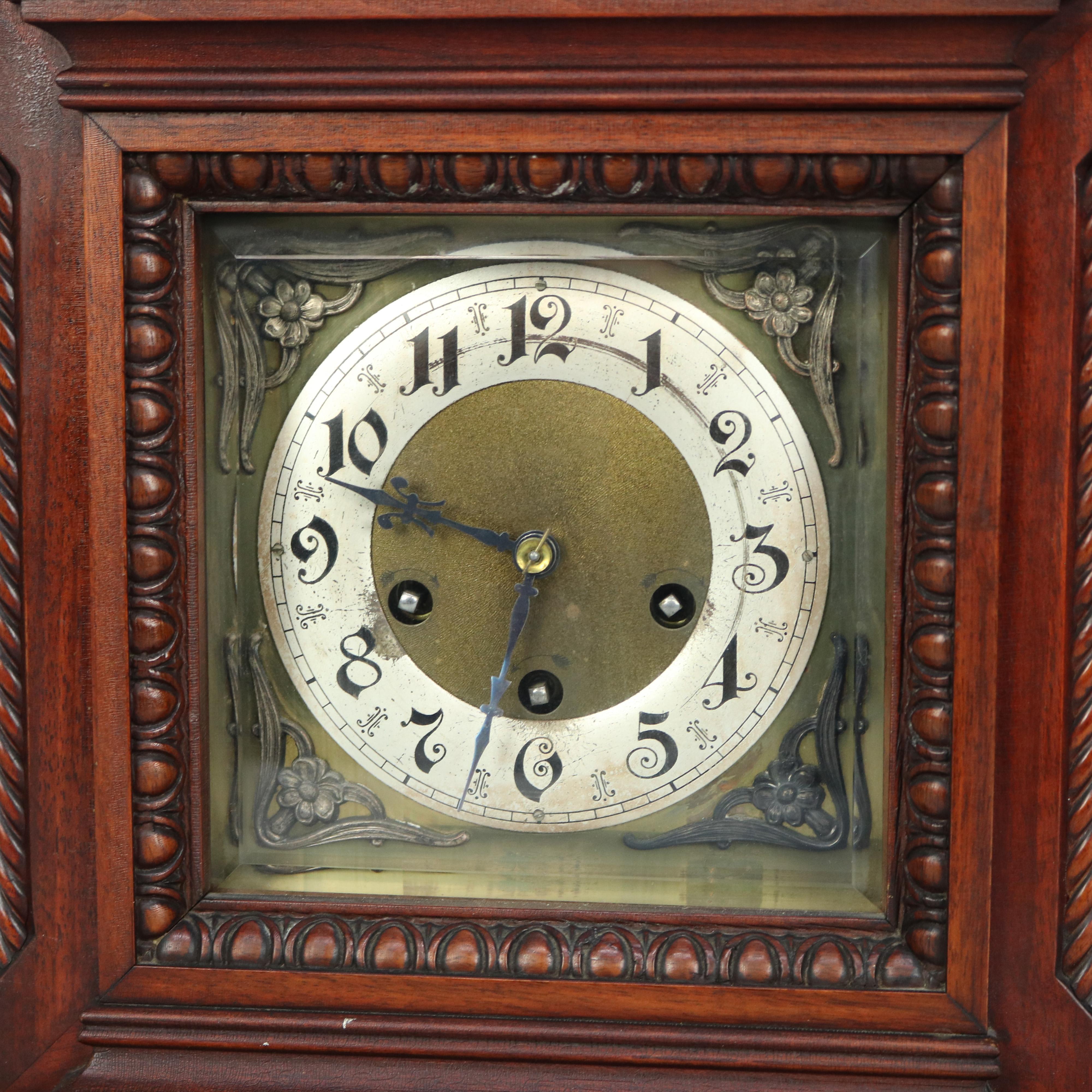 An antique German bracket clock by Junghans offers flame mahogany case in architectural form with incised crest over face with chime and speed dials and having cast floral corbels, door with carved egg-and-dart trimming, original label as