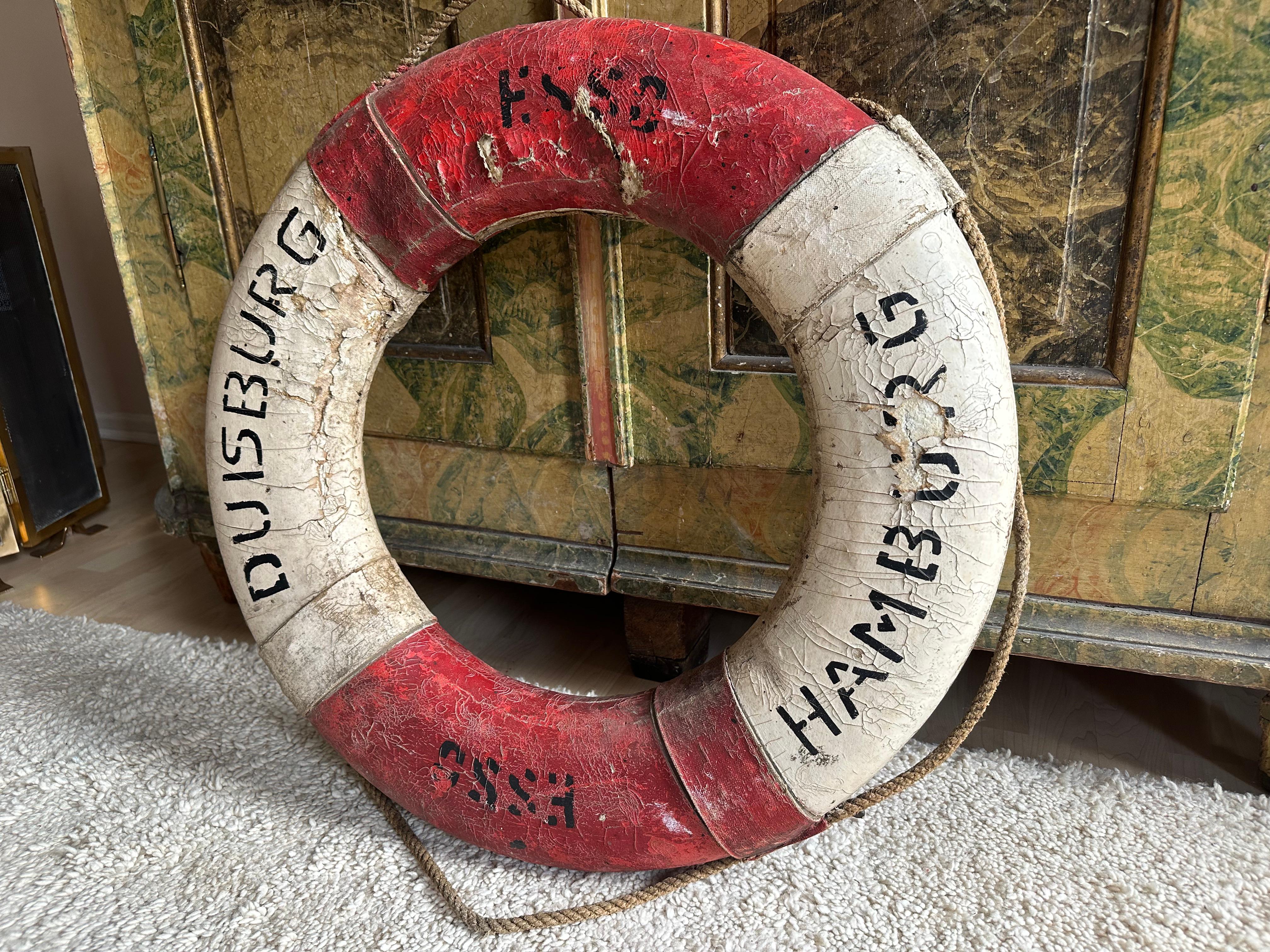 Diese authentische deutsche Rettungsboje aus dem 20. Jahrhundert ist ein seltenes maritimes Artefakt mit außergewöhnlichem dekorativen Reiz. Das Stück weist eine reiche, verwitterte Patina auf, die von seiner langen Geschichte auf See zeugt und es