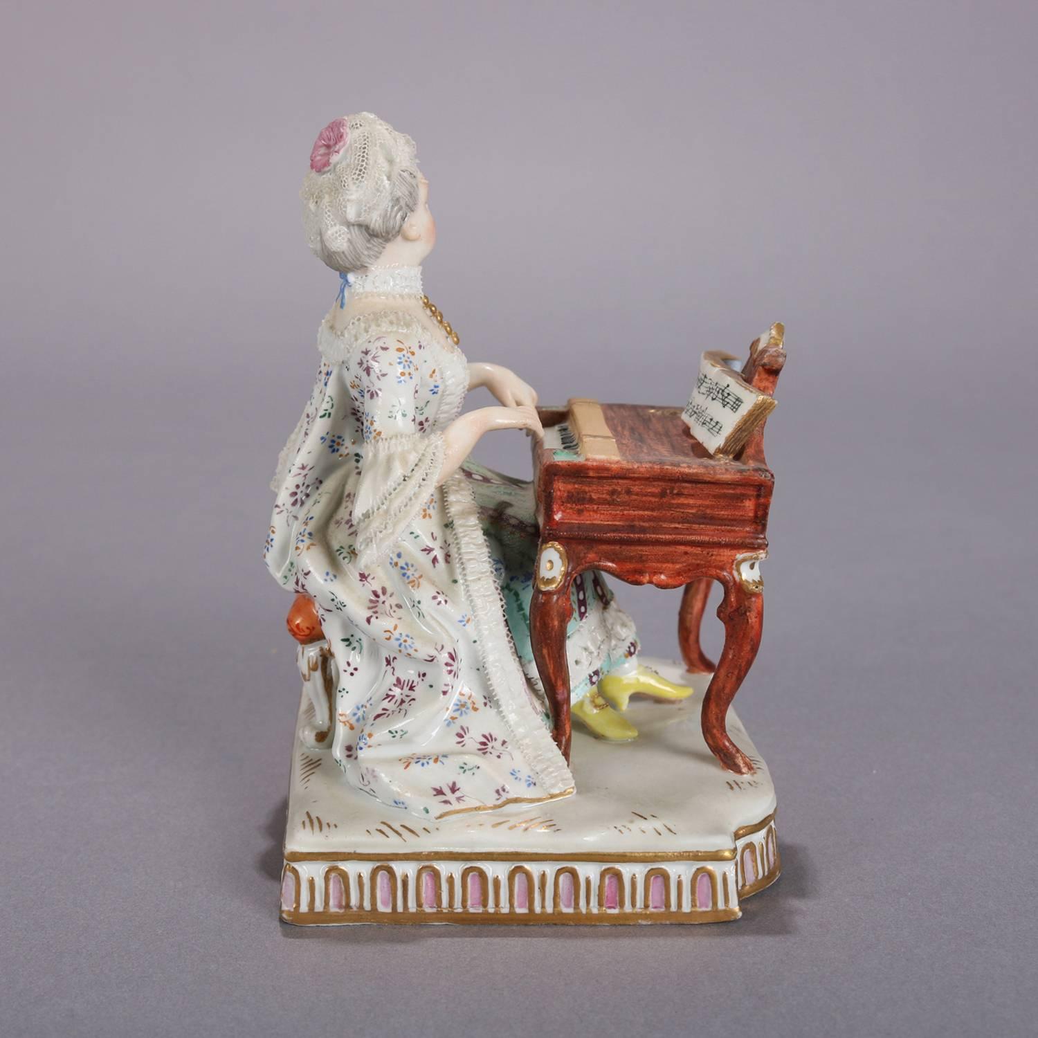 Antique German Meissen figural group features pianist playing her clavichord piano, hand-painted with gilt highlights, crossed sword mark on base, circa 1880.

Measures: 5