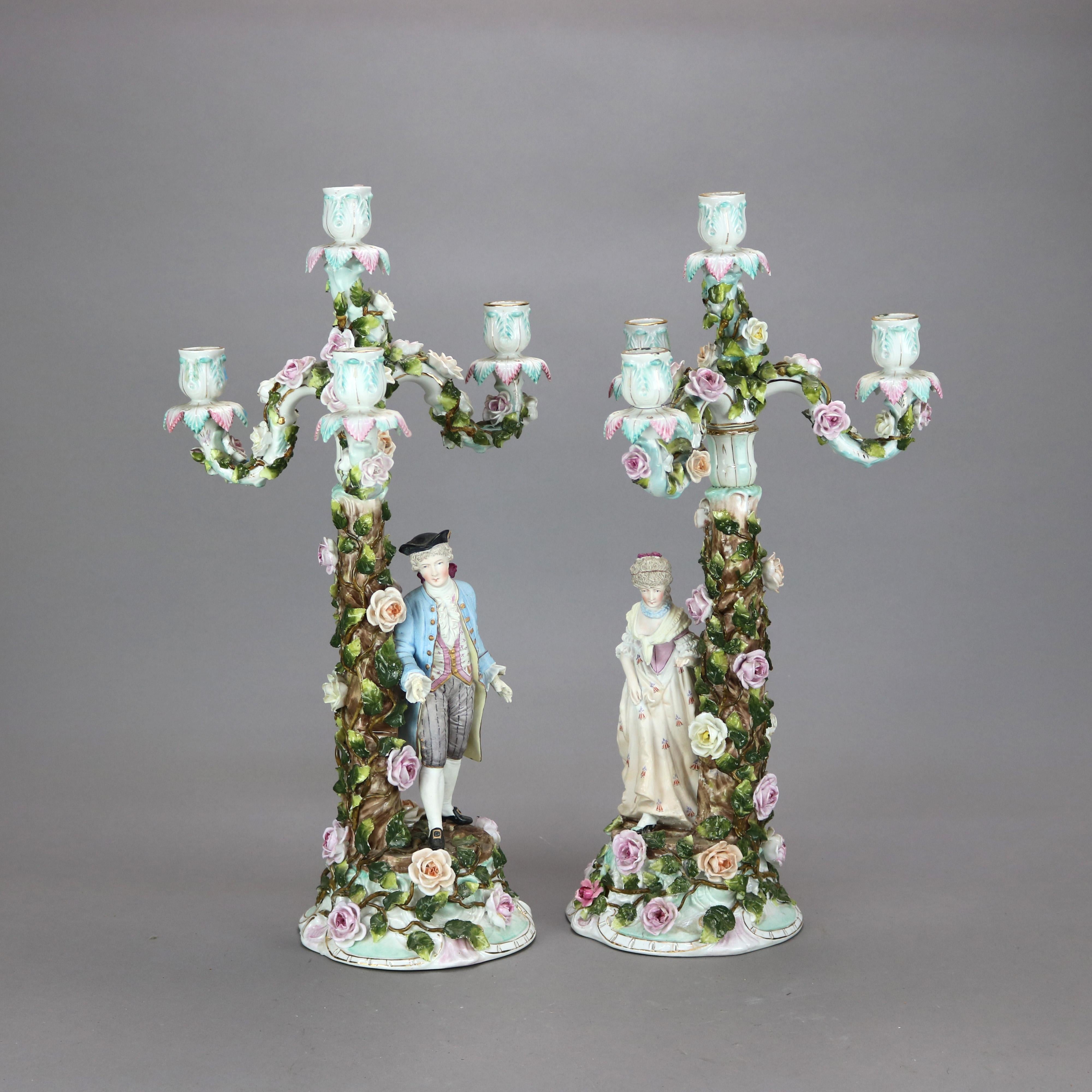 An antique pair of German figural candelabra in the manner of Meissen offer hand painted porcelain construction with man and woman in countryside setting and having three s-scroll arms terminating in candle sockets and surrounding central socket,