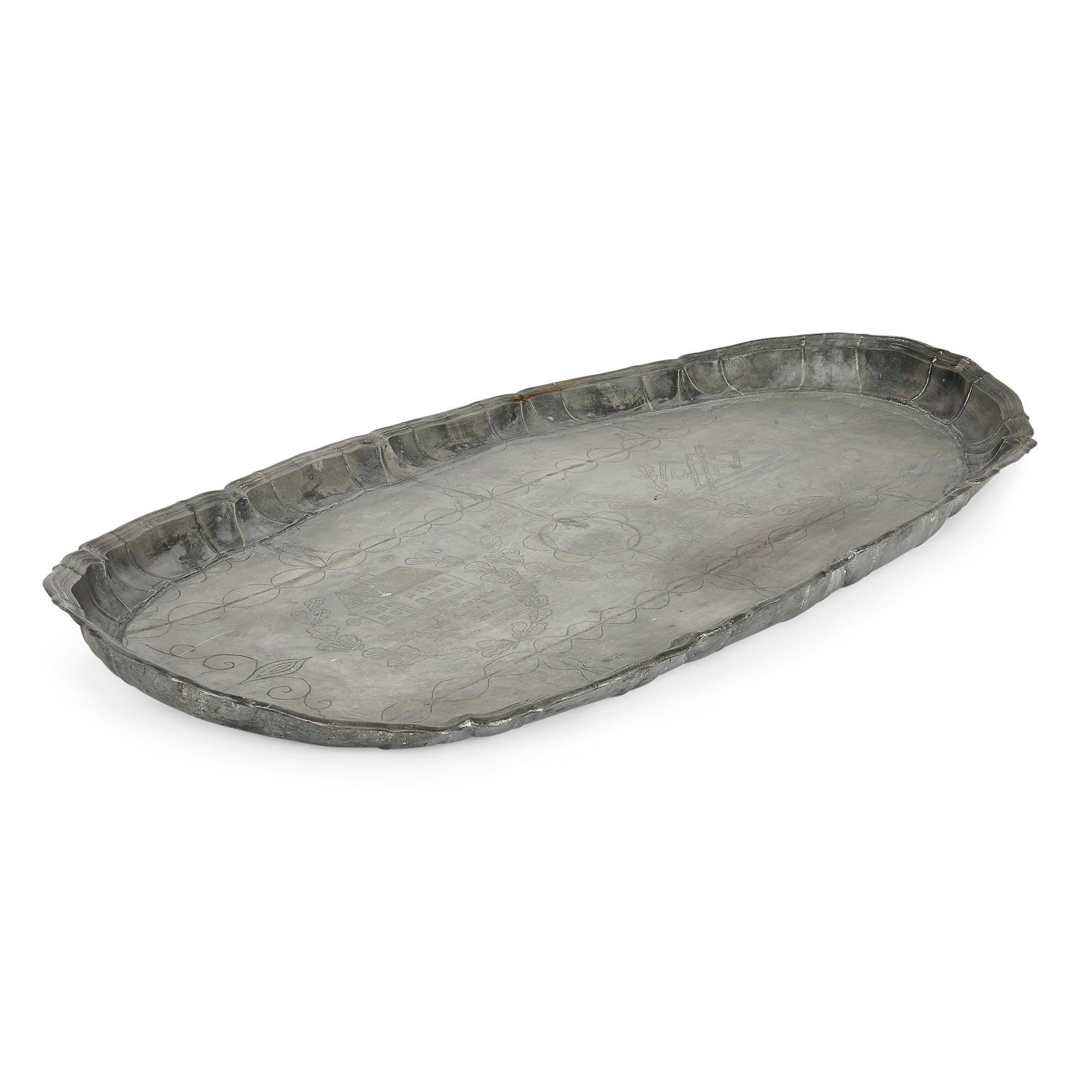 Antique German naive engraved pewter tray
German, c. 1743
Height 4.5cm, width 98cm, depth 56cm

This fine German tray is crafted from pewter, an alloy of tin long used to create decorative pieces. The tray is of irregular shape, and features a