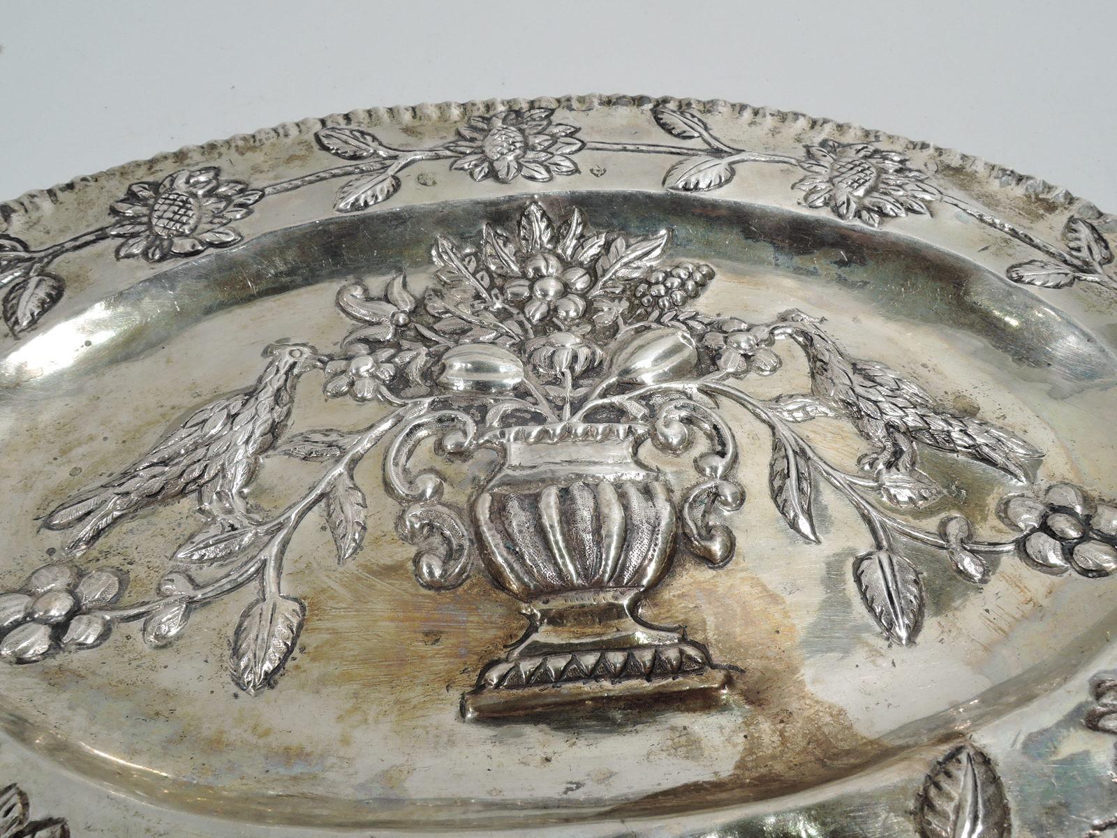 German Neoclassical silver tray, 18th century. Oval with crimped rim. Embossed flower basket in well and garland on shoulder. A naïve representation of modish ornament. Marked. Weight: 5.5 troy ounces.