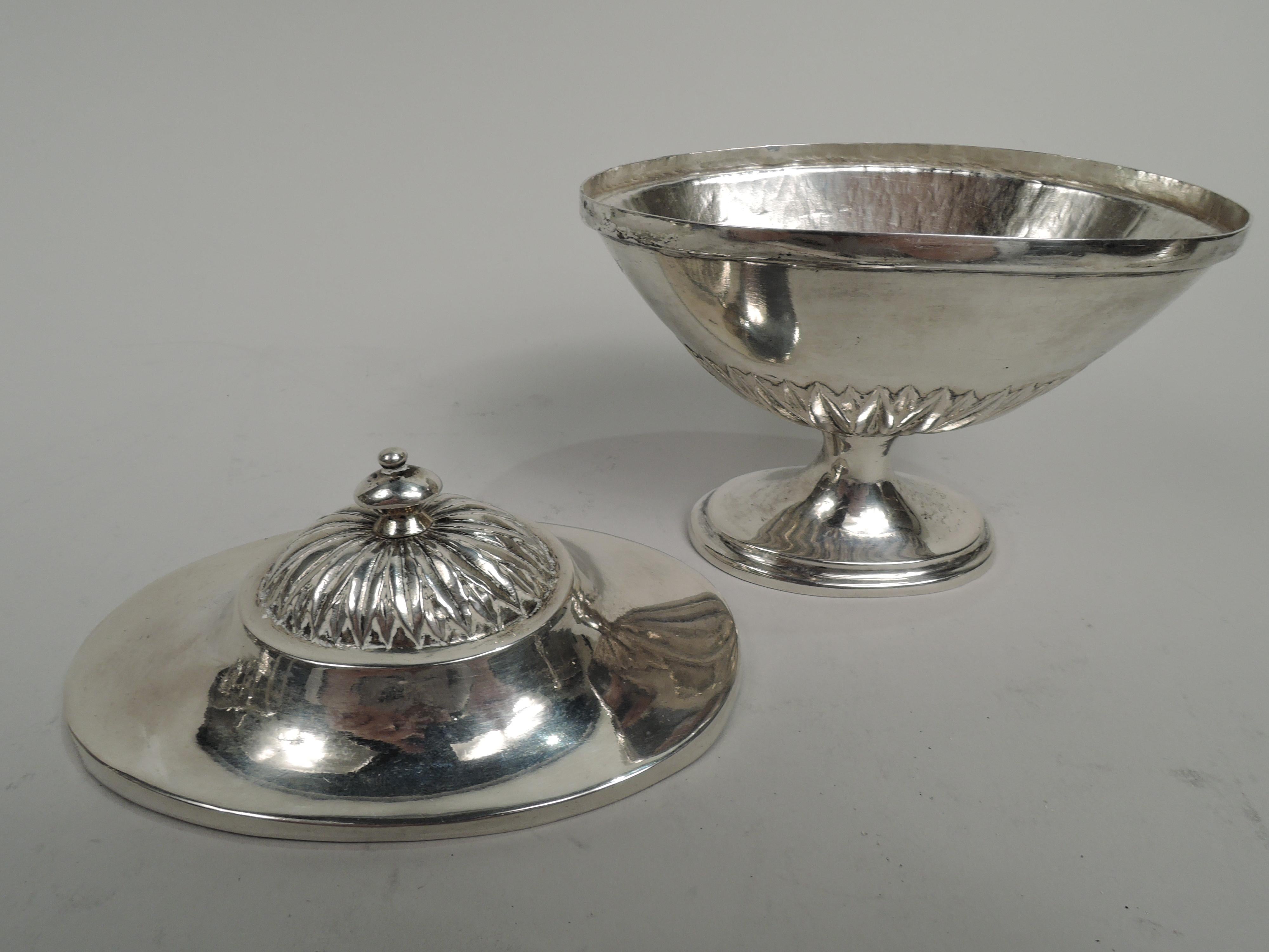 German Neoclassical silver urn, 18th century. Oval tapering bowl on raised and stepped foot. Cover domed with vasiform finial. Chased imbricated leaf border at bowl bottom; same on cover dome. Visible hammering and handwork. Marked. Weight: 5 troy